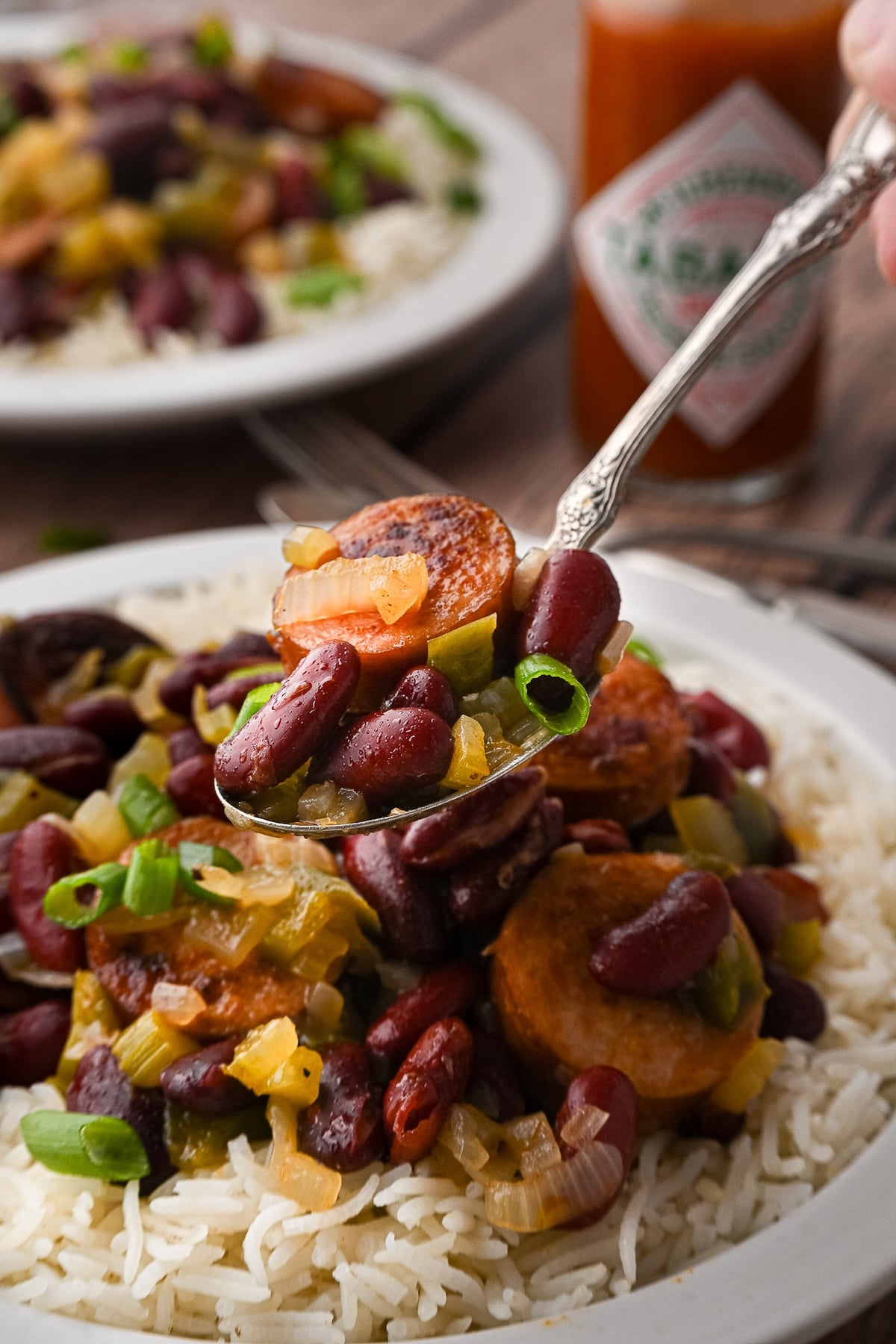 A spoon lifting a bite of red beans and sausage.