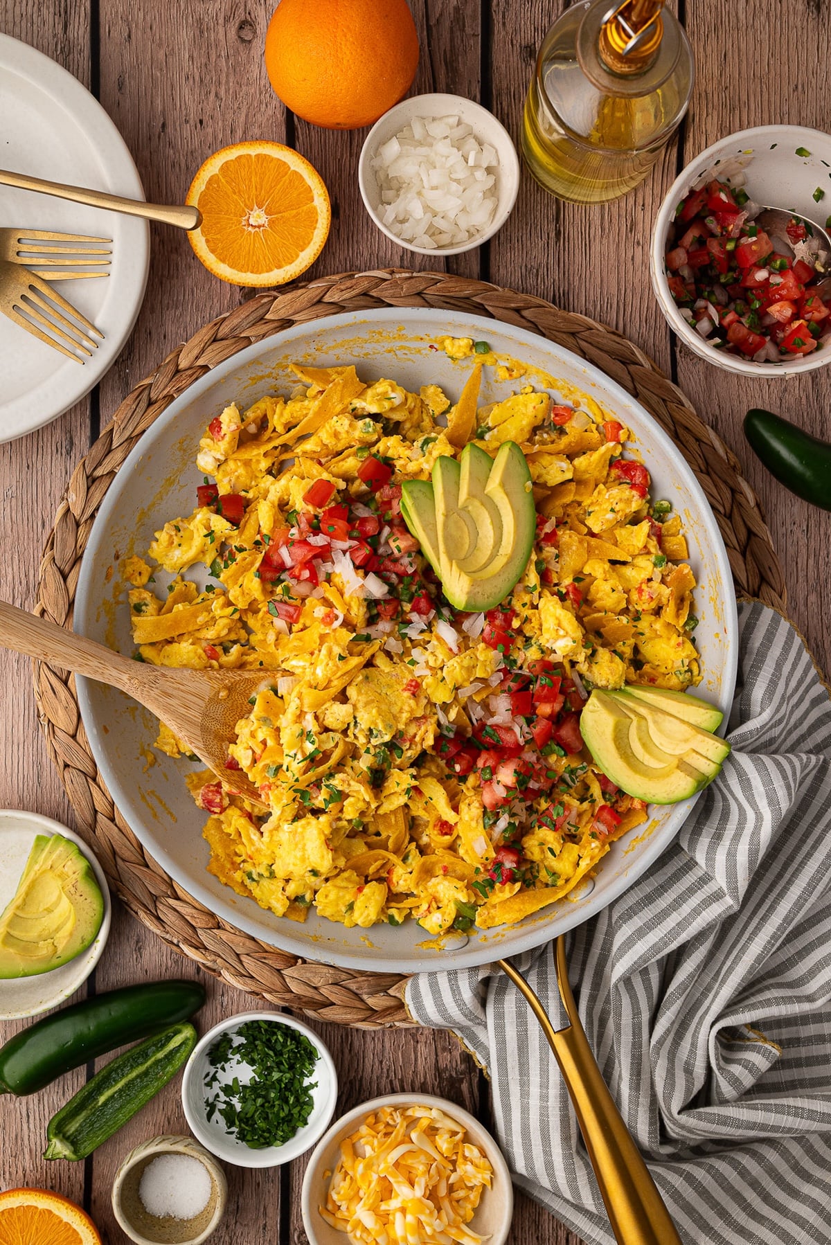A skillet full of prepared Tex-Mex Style Migas garnished with Roma tomatoes and avocado slices.
