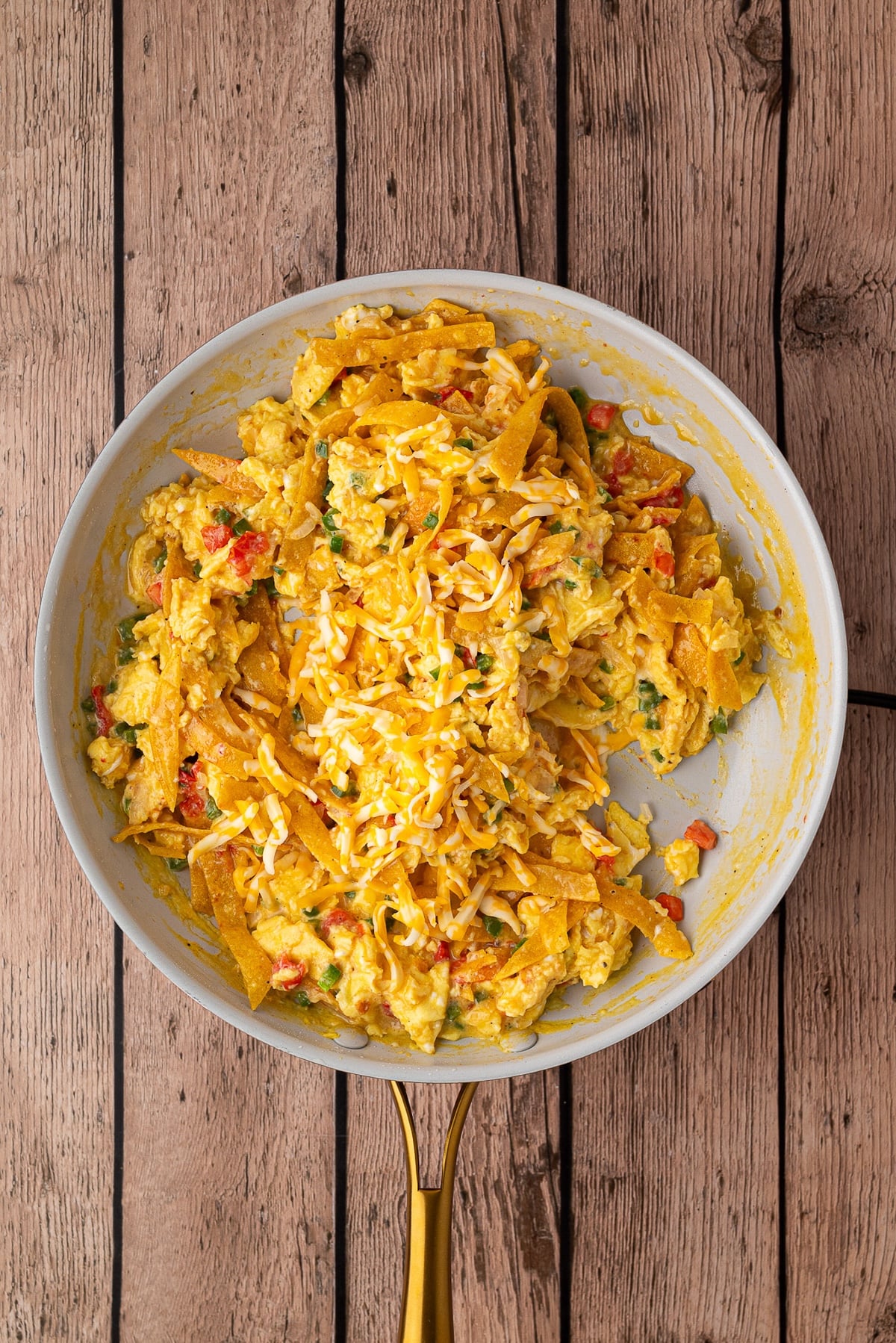 Adding shredded cheddar cheese to eggs just before they are finished.