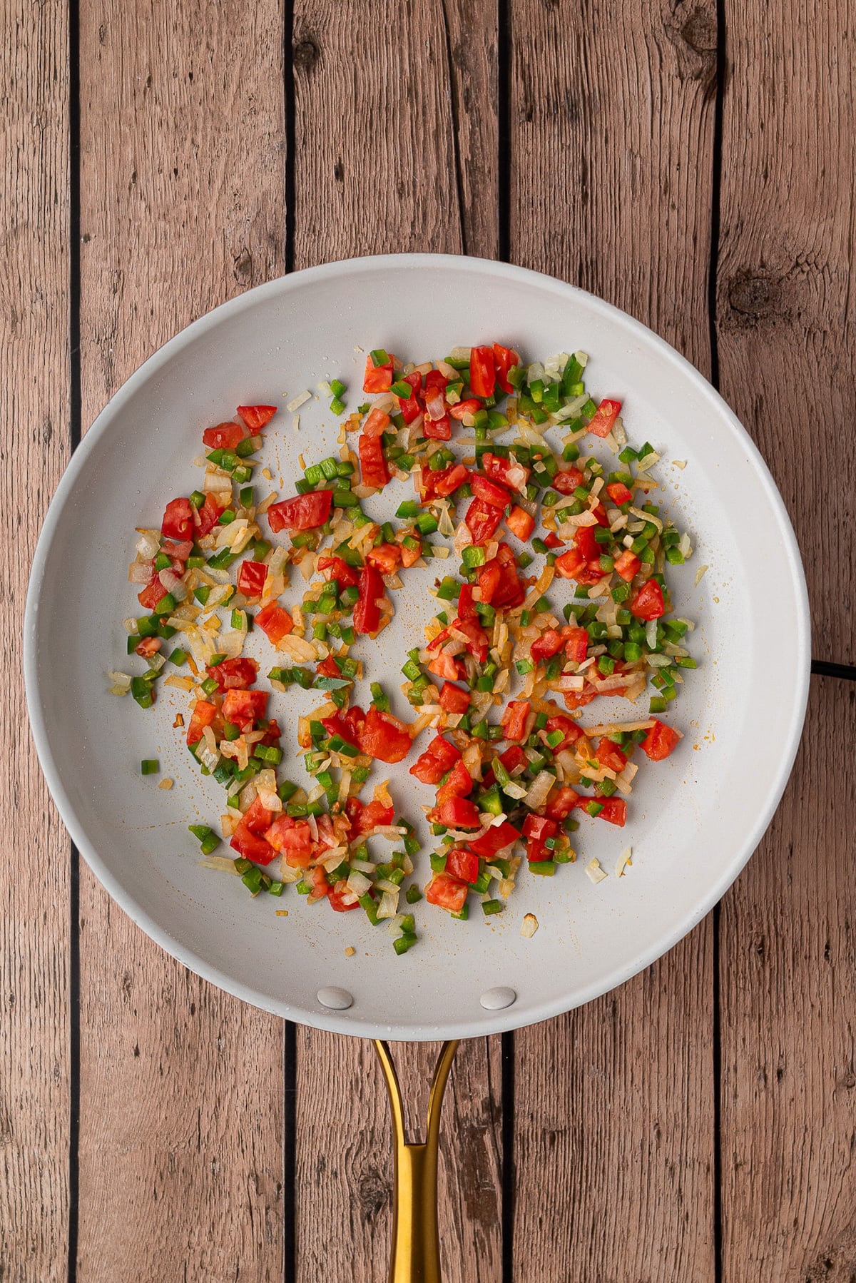 Sautéing jalapenos, onion and Roma tomatoes in a skillet for Tex-Mex breakfast.