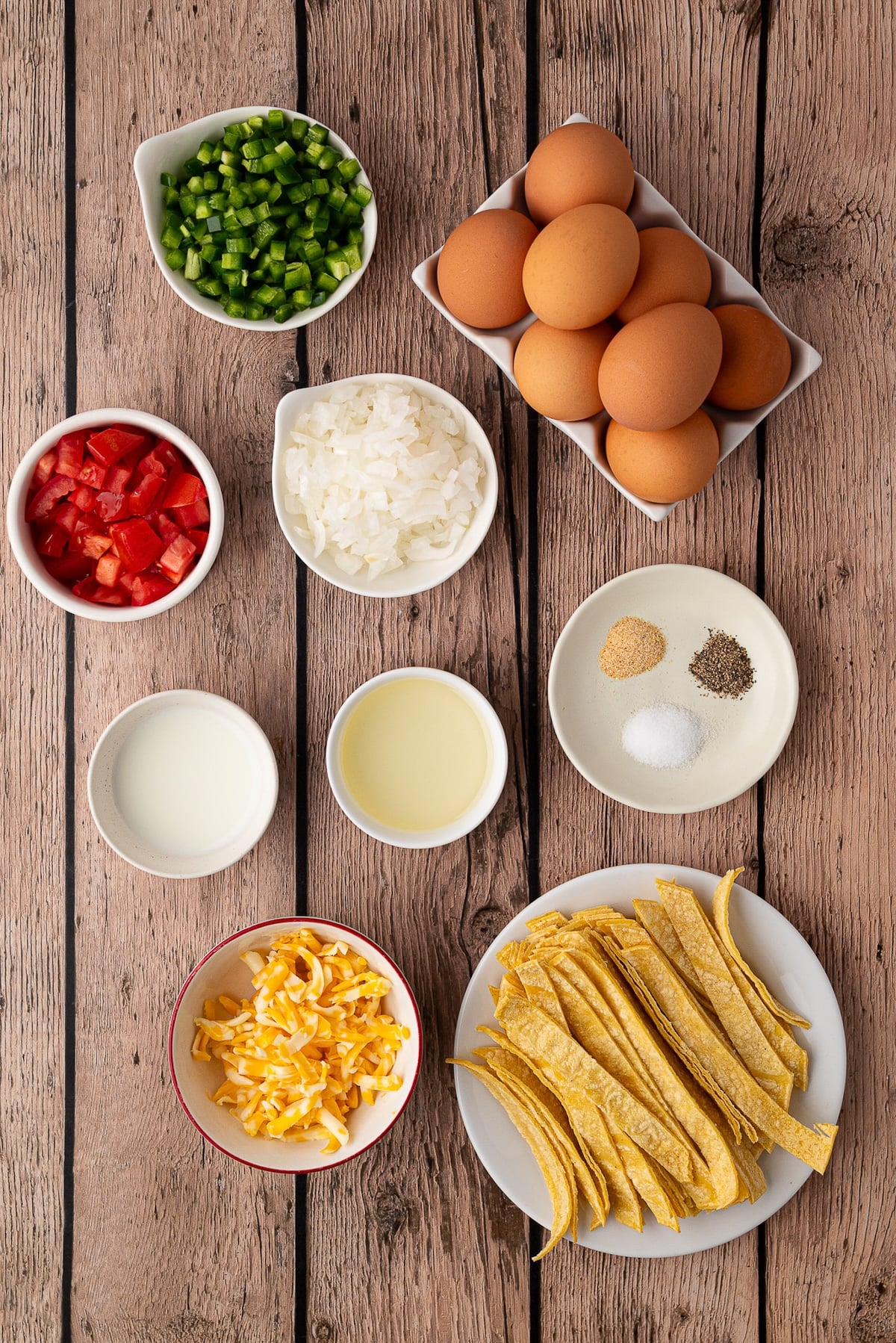 Ingredients for Tex-Mex Migas including eggs, jalapeños, tomato, corn tortillas, onions and shredded cheese.