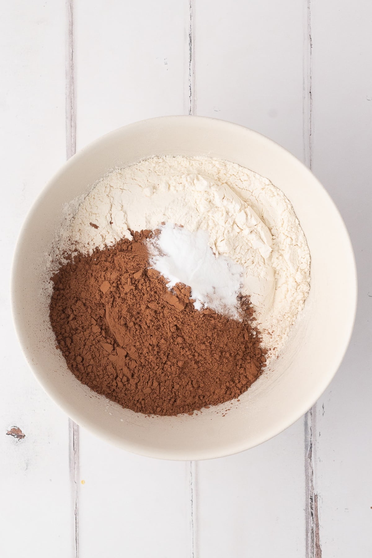 Mixing together dry ingredients including carefully measured cocoa powder together.