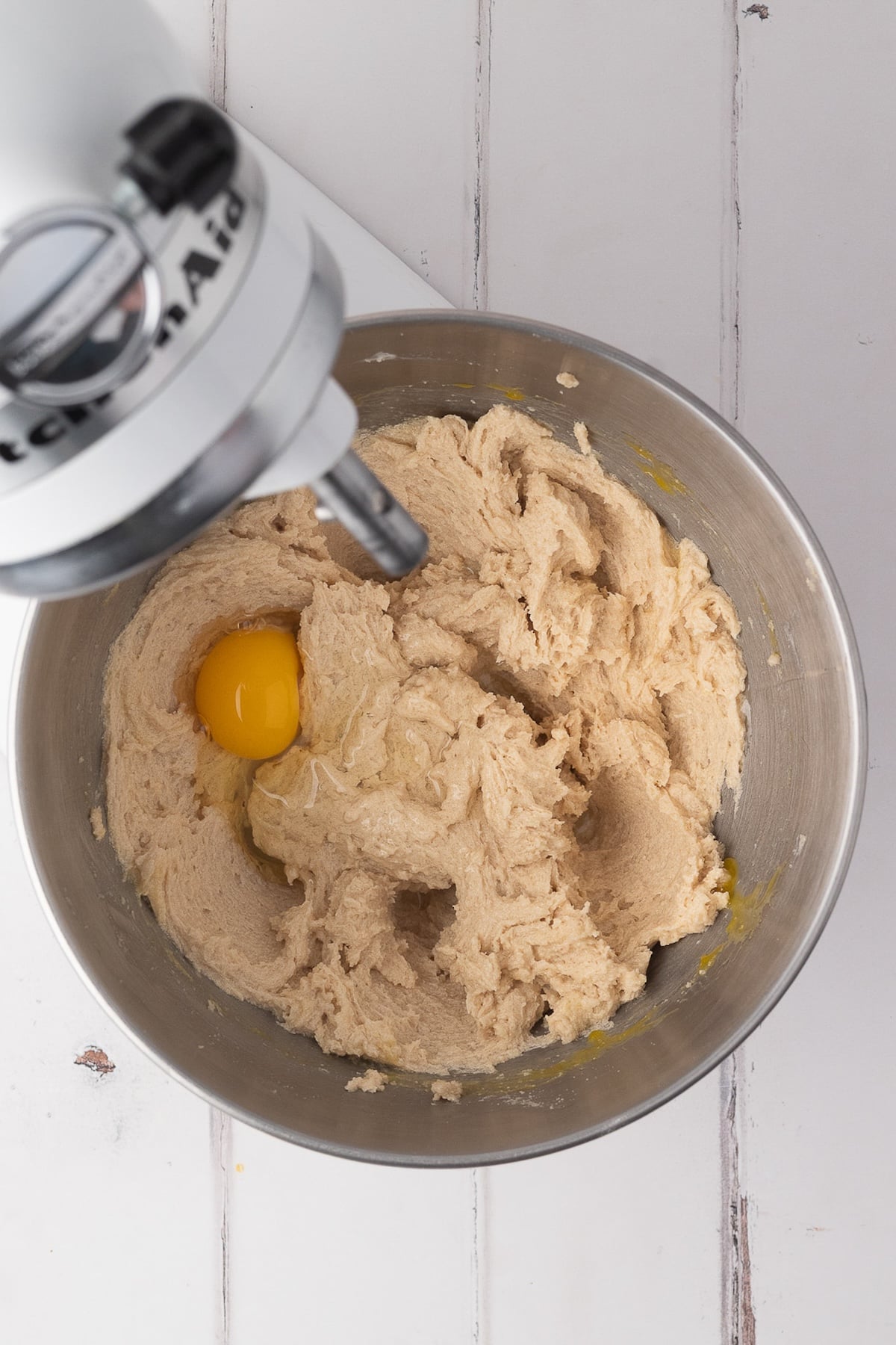 A stand mixer whisking together softened butter and sugars and eggs until light and fluffy for cookie dough.