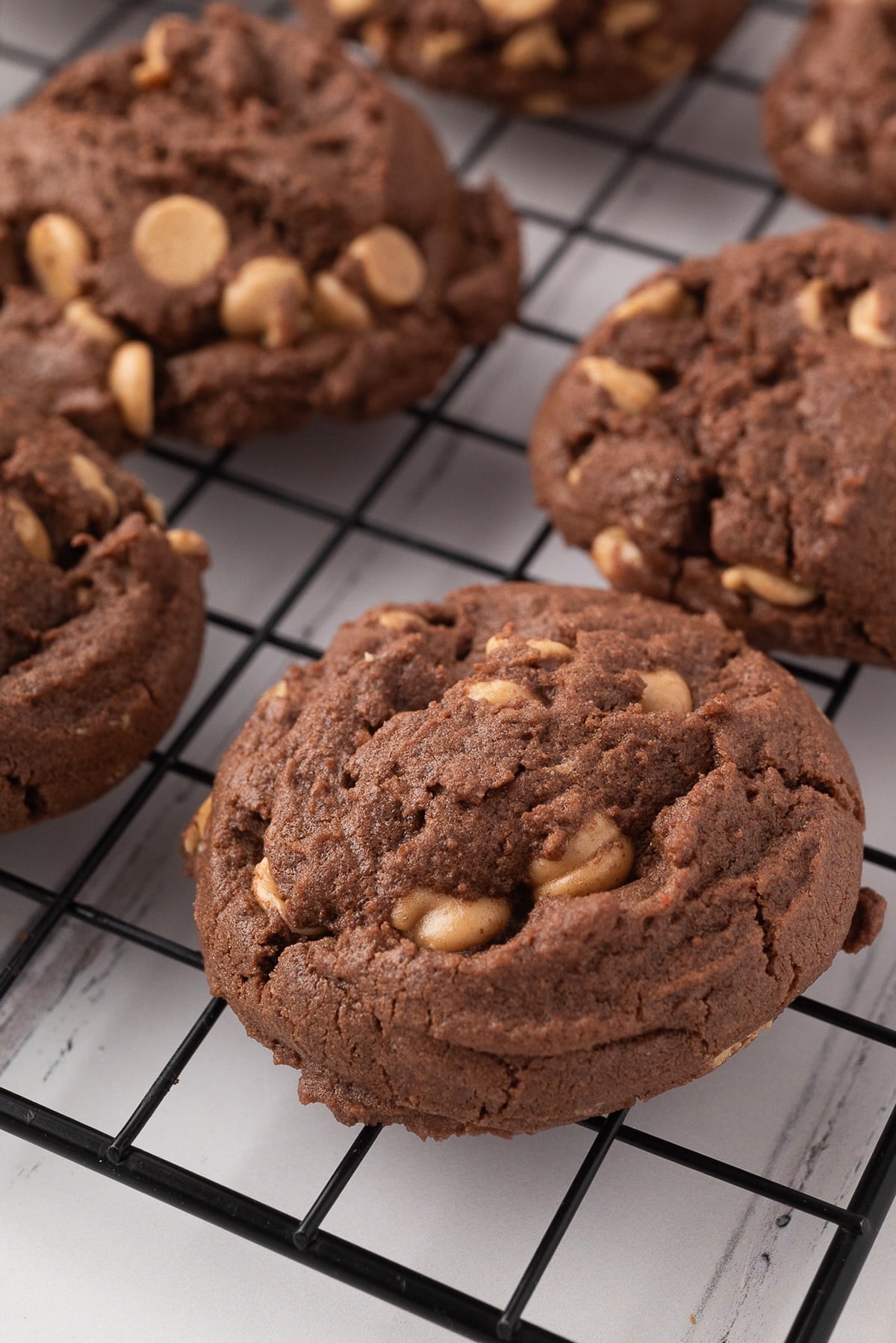 Chocolate dough with peanut butter chip cookies cool on a rack.