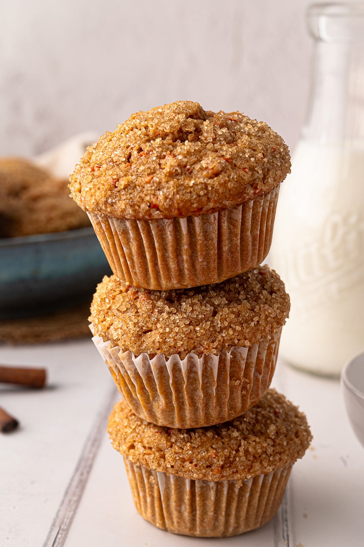 A stack of moist, nut-free carrot muffins on a cooling rack, featuring a tall bakery-style rise from a 400°F oven.
