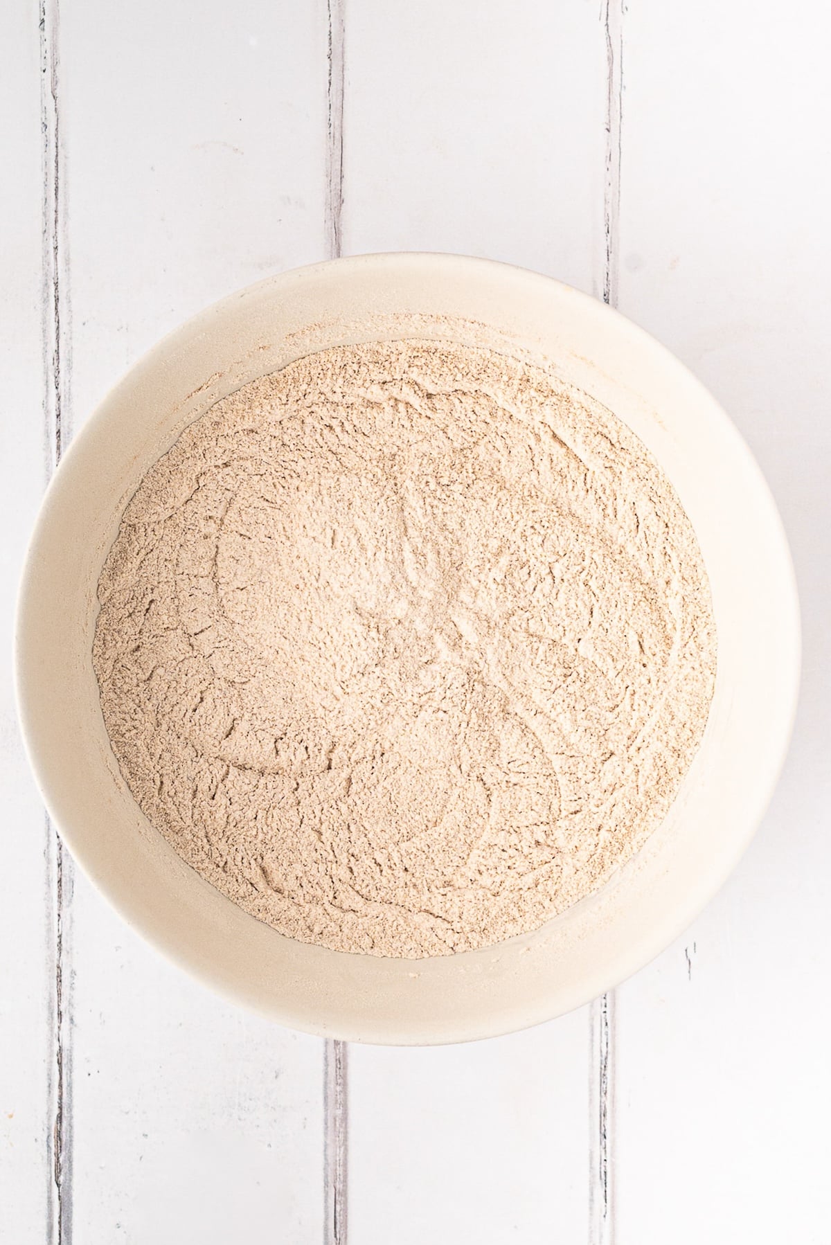 Whisking King Arthur white whole wheat flour with cinnamon, ginger, and nutmeg in a ceramic mixing bowl.