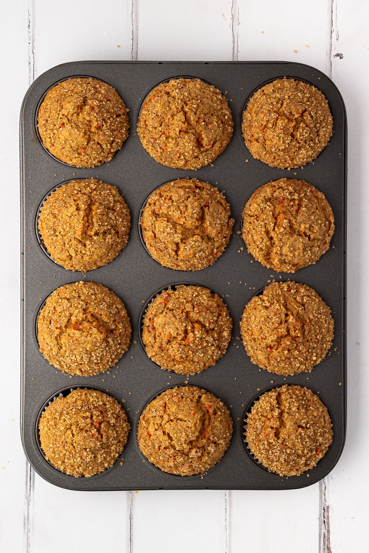 A dozen tall, baked carrot muffins fresh out of a 400°F oven, showing a perfect rise and texture.