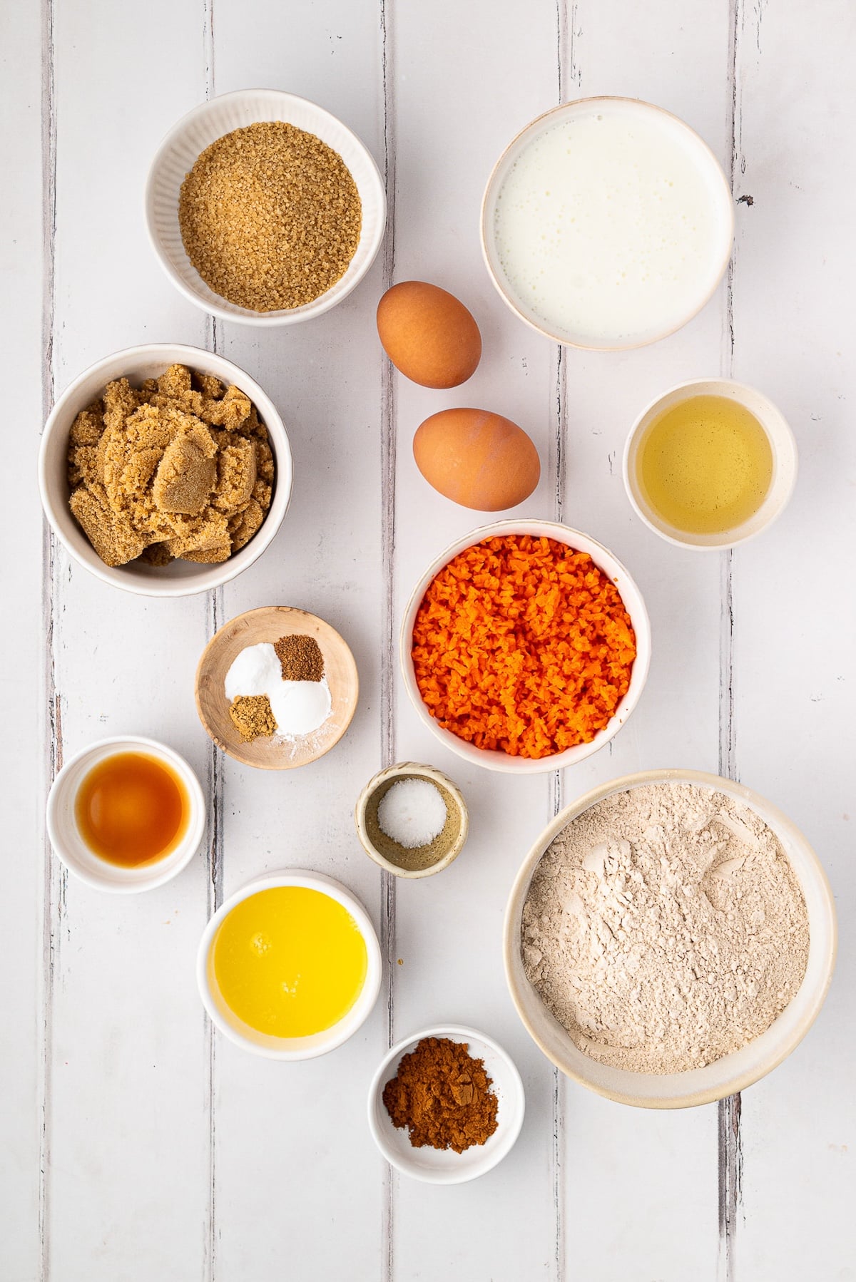 A flat-lay of ingredients for Whole Wheat Carrot Muffins, featuring King Arthur White Whole Wheat Flour, whole buttermilk, and fresh carrots.