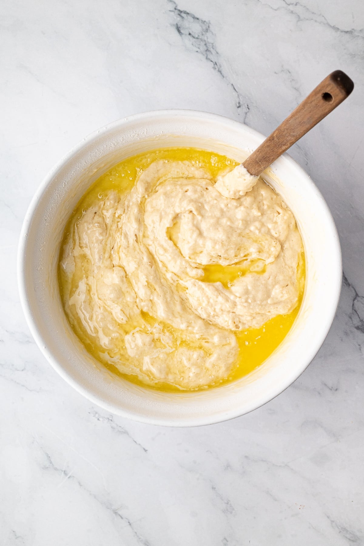 Slowly stirring melted butter and oil into thick buttermilk waffle batter until just incorporated.