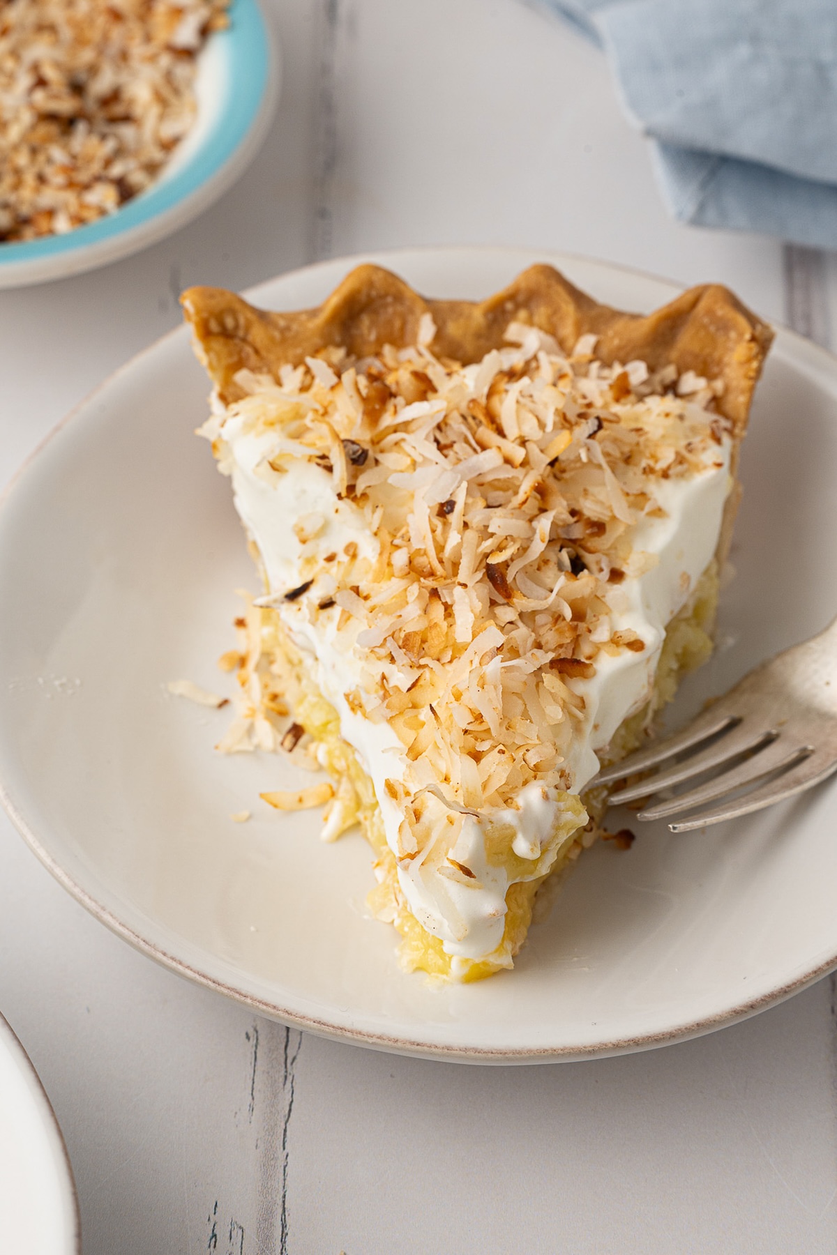 A close-up of a slice of easy coconut pie , focusing on the contrast between the dense, baked custard-like pie filling and the light, powdered sugar sweetened whipped topping