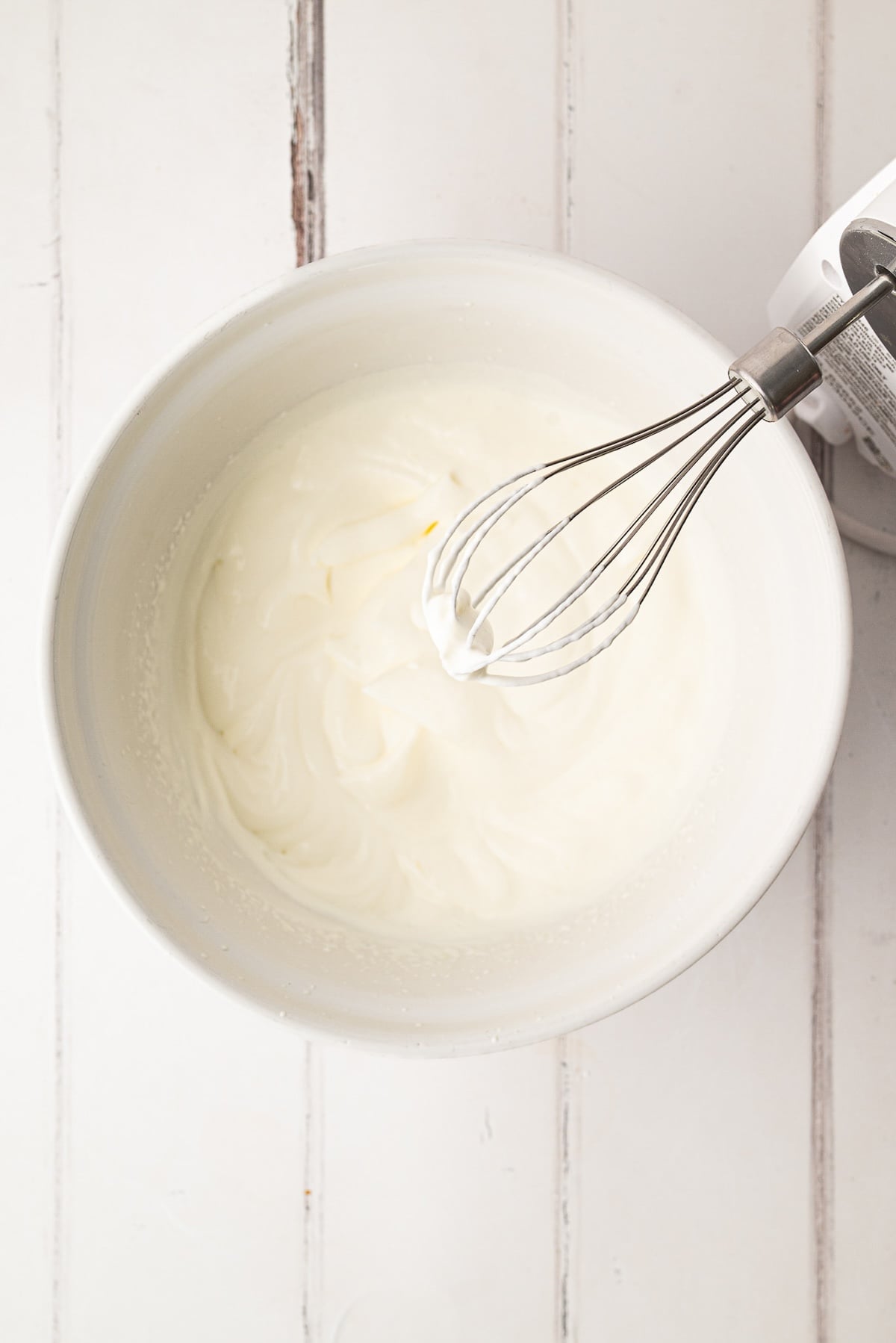 Whipping together powdered sugar and heavy cream to make a lightly sweetened chilled pie topping.