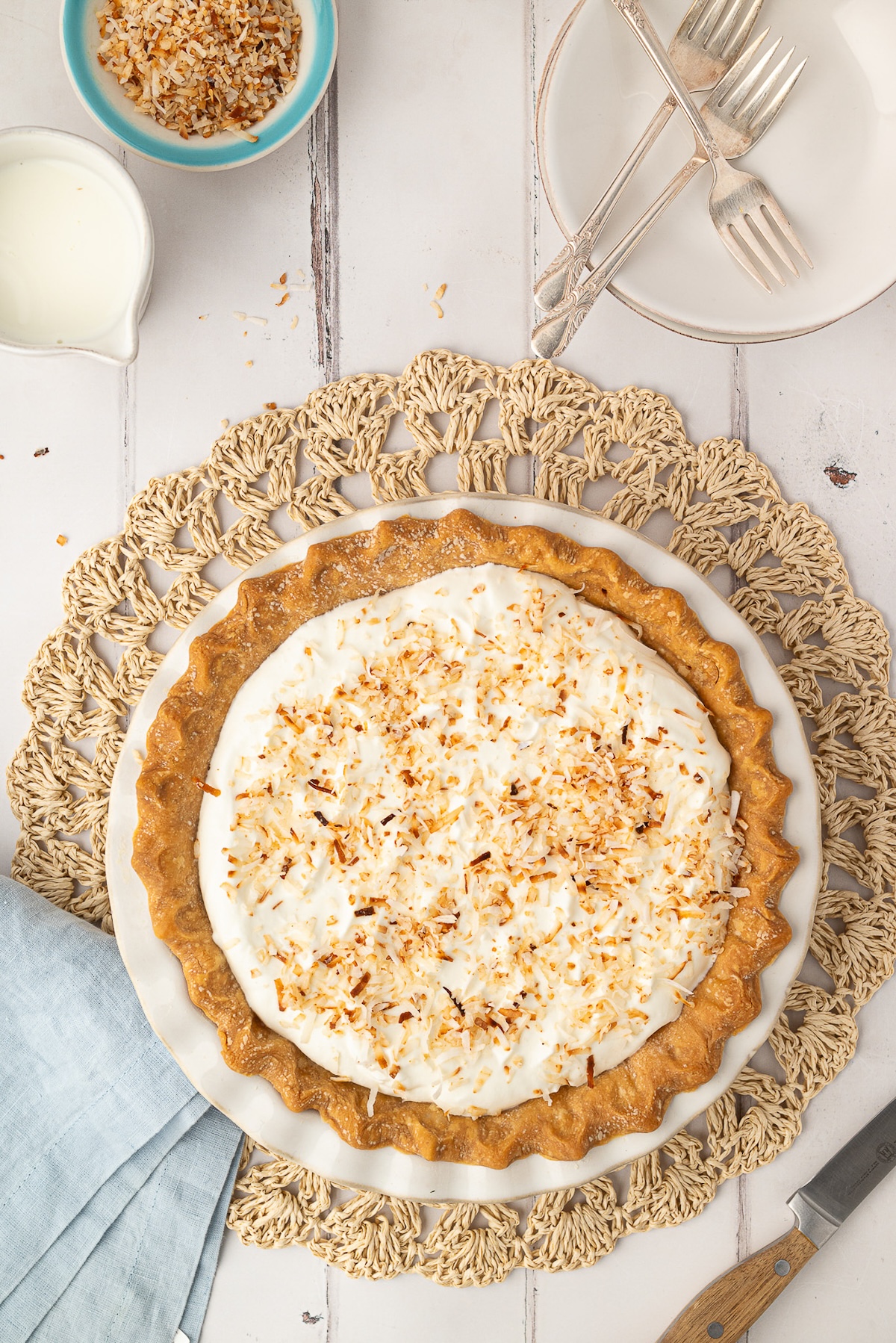 A whole baked coconut pie in a pie dish, finished with a fluffy whipped cream topping and golden toasted coconut. A classic Southern dessert perfect for Easter or any occasion.