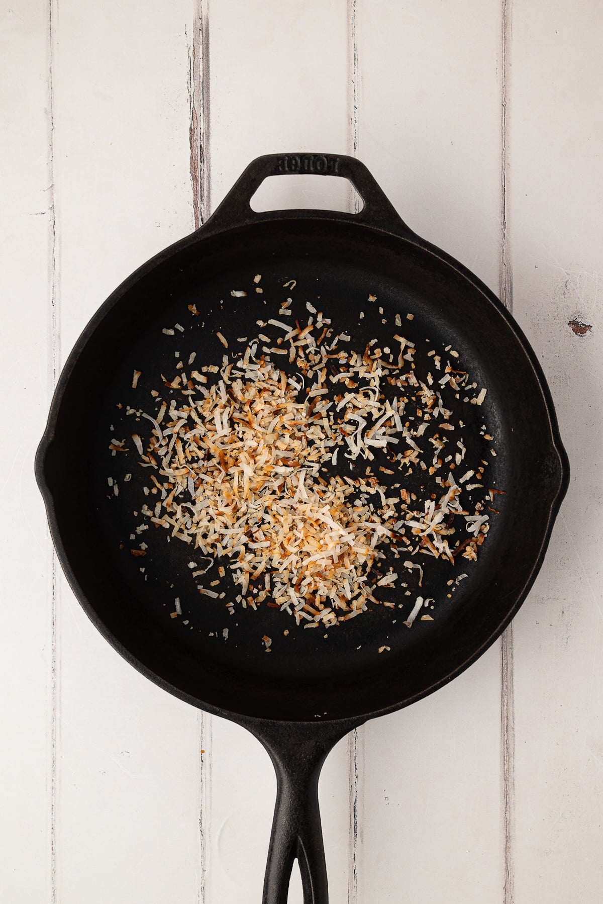 Toasting sweetened shredded coconut flakes in a skillet as a garnish for the whipped cream pie topping.