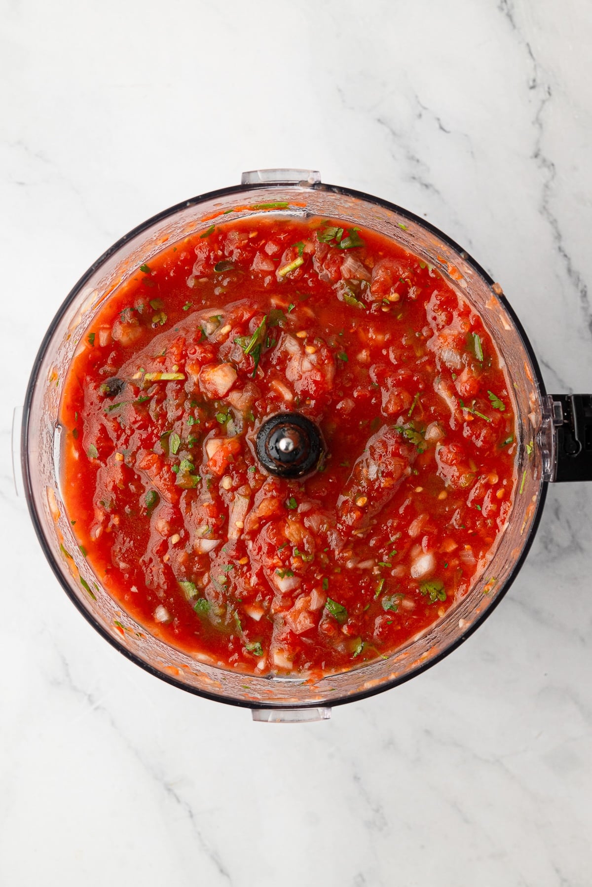 Close-up of chunky, authentic Texas restaurant-style salsa showing flecks of cilantro and roasted peppers.
