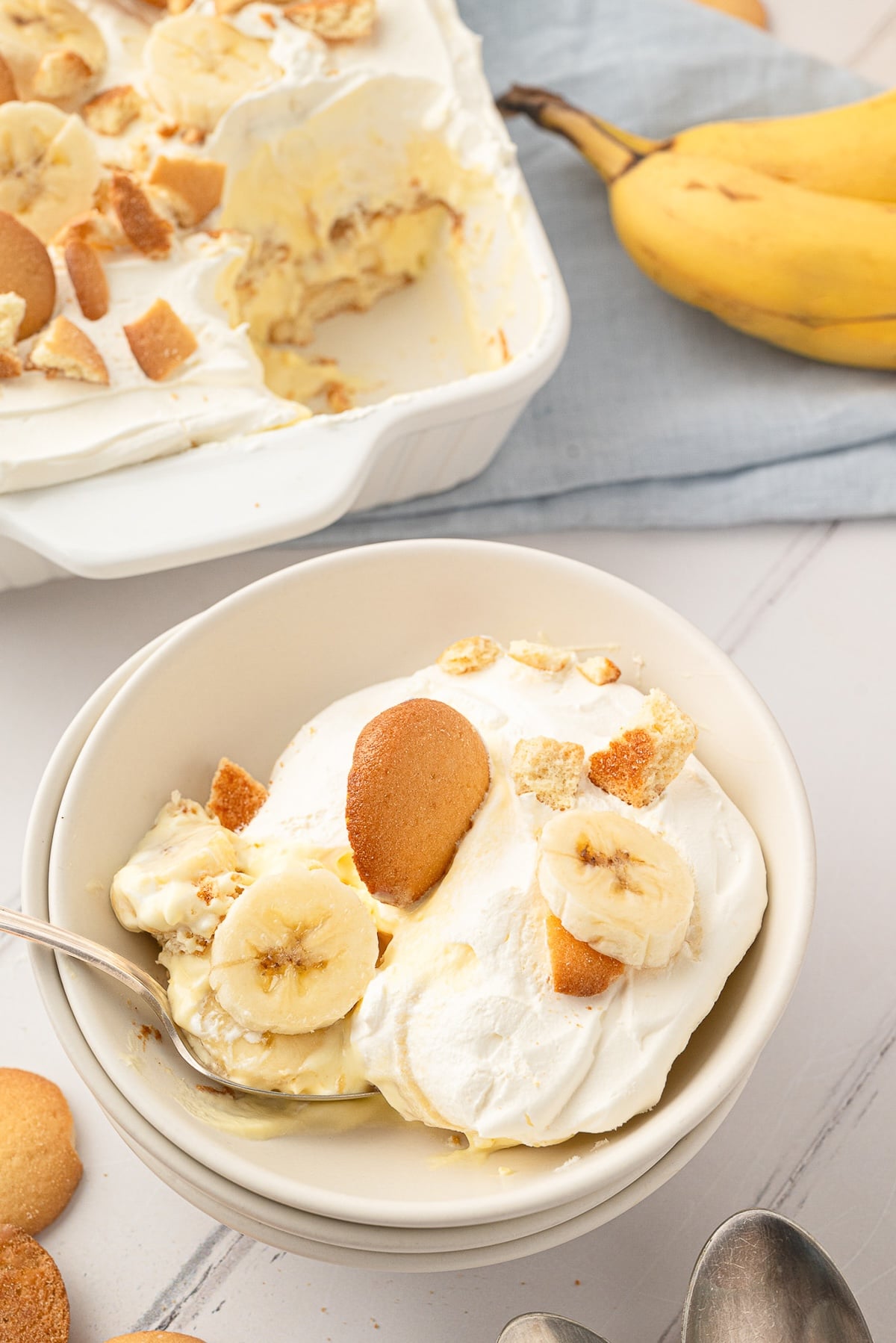 A scoop of light and fluffy no-bake banana pudding layered with fresh bananas and vanilla wafers served in a bowl.