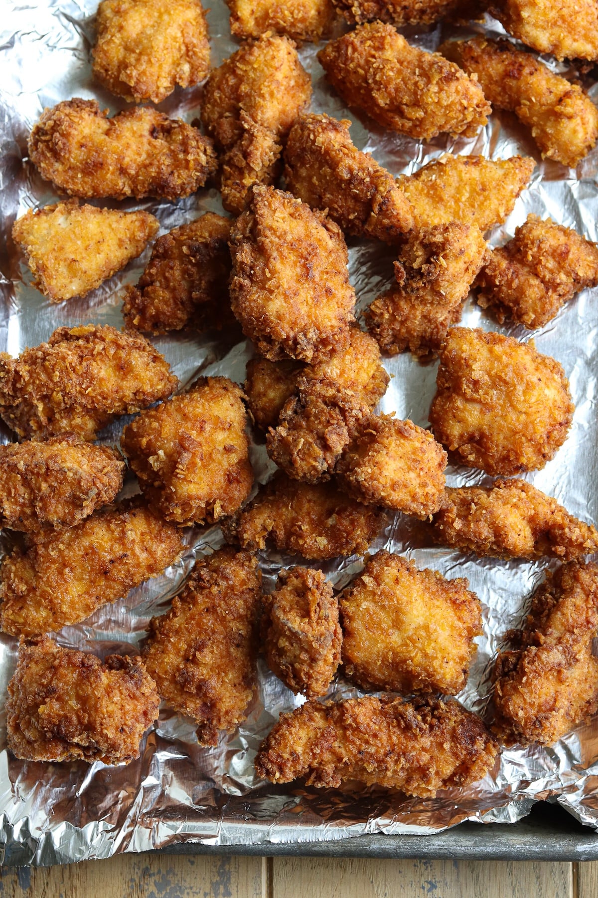 Crispy, golden-brown cornflake fried chicken nuggets resting on a baking sheet.