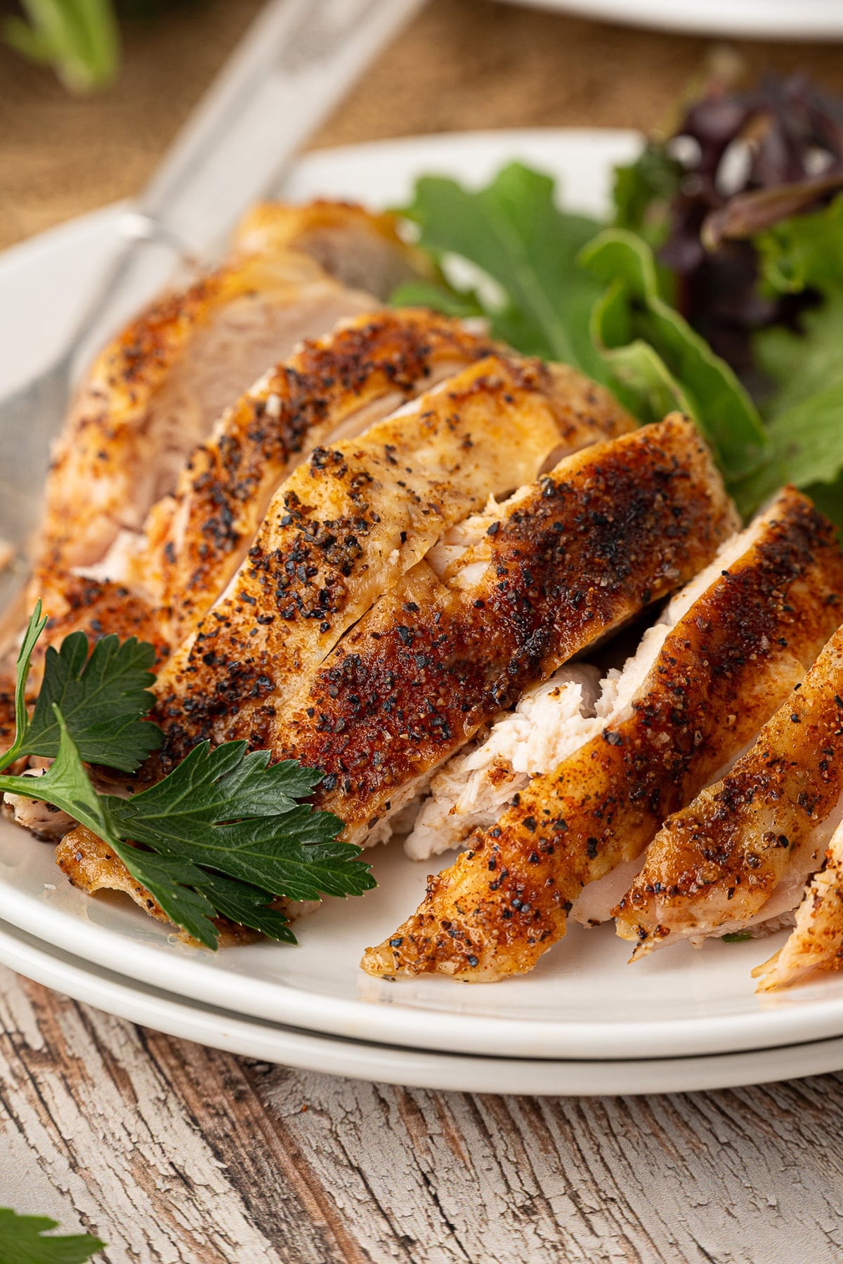 Golden brown oven-roasted bone-in split chicken breasts garnished with fresh herbs sliced on a dinner plate.