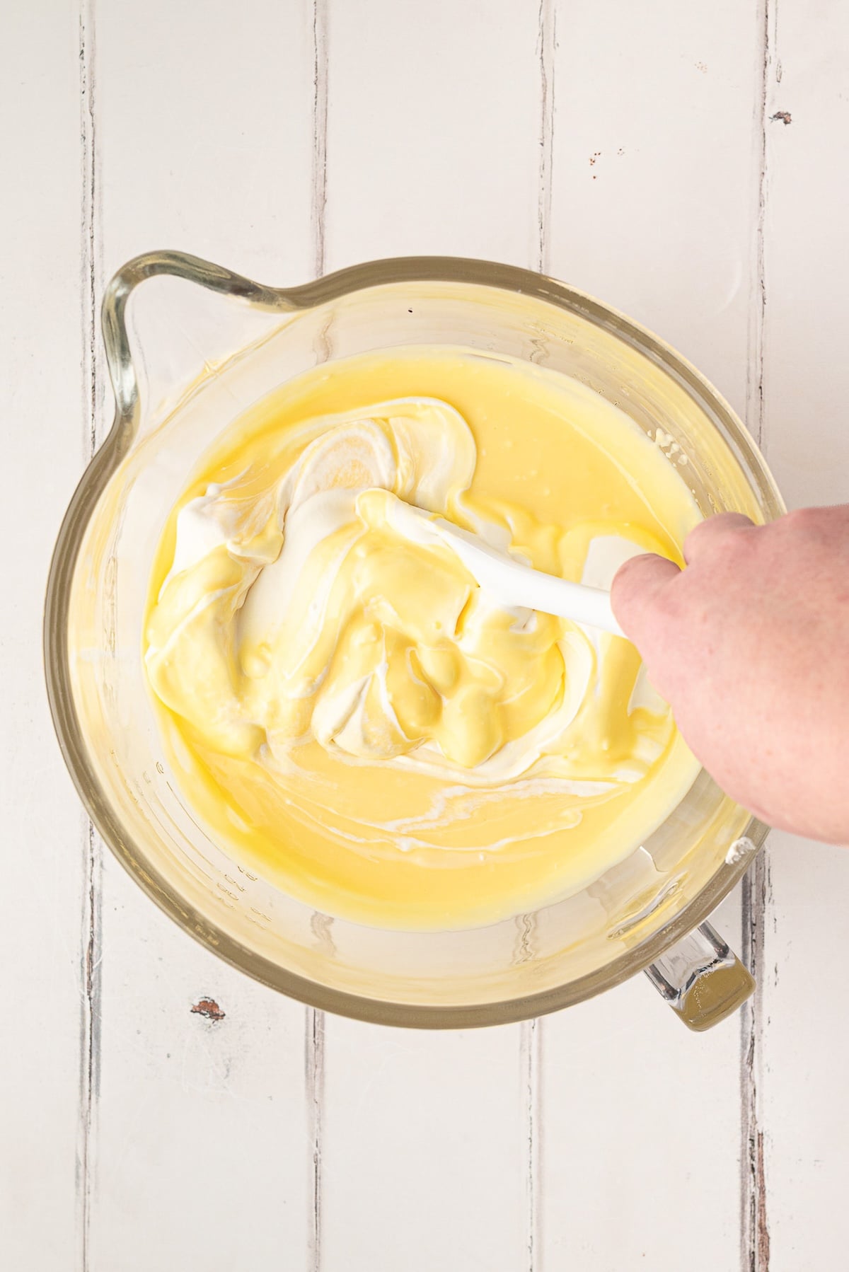 Adding prepared vanilla pudding to the softened cream cheese and condensed milk.