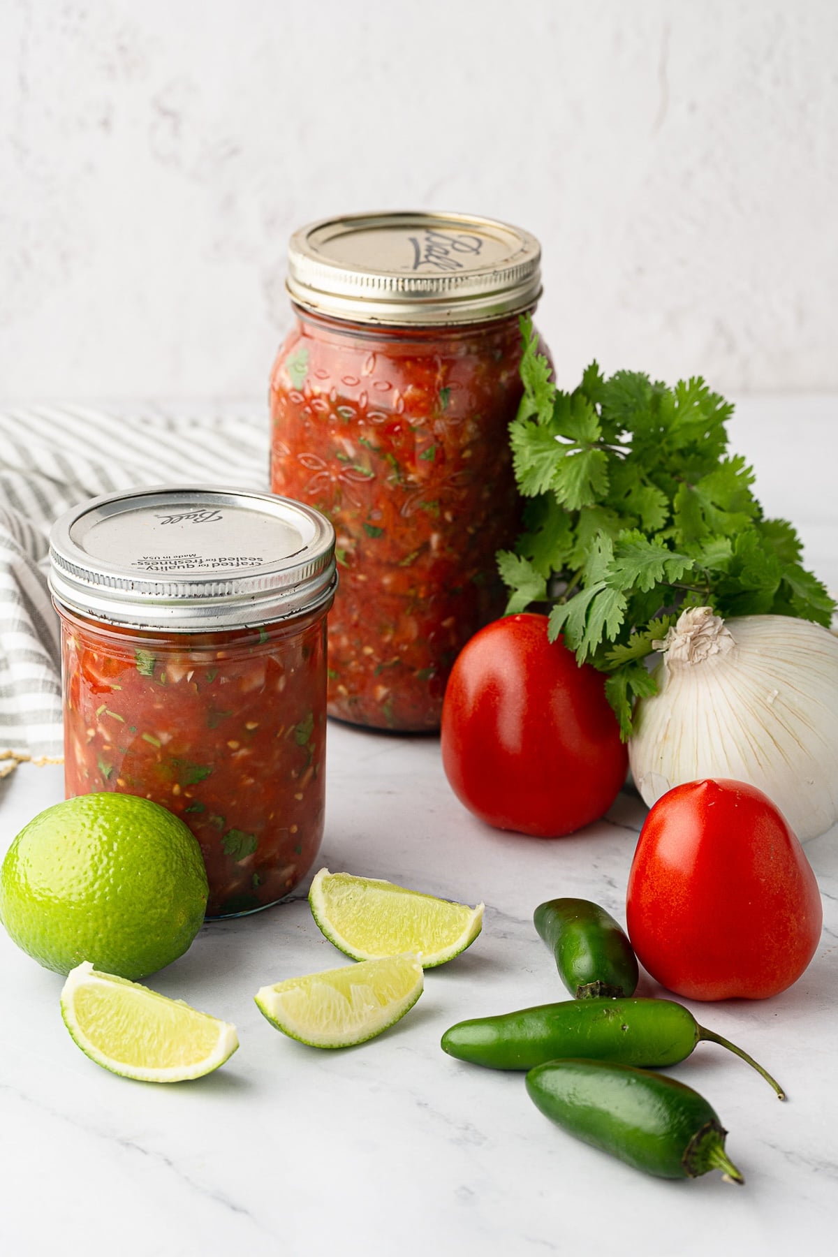 Two glass mason jars filled with homemade salsa ready for refrigerator storage.