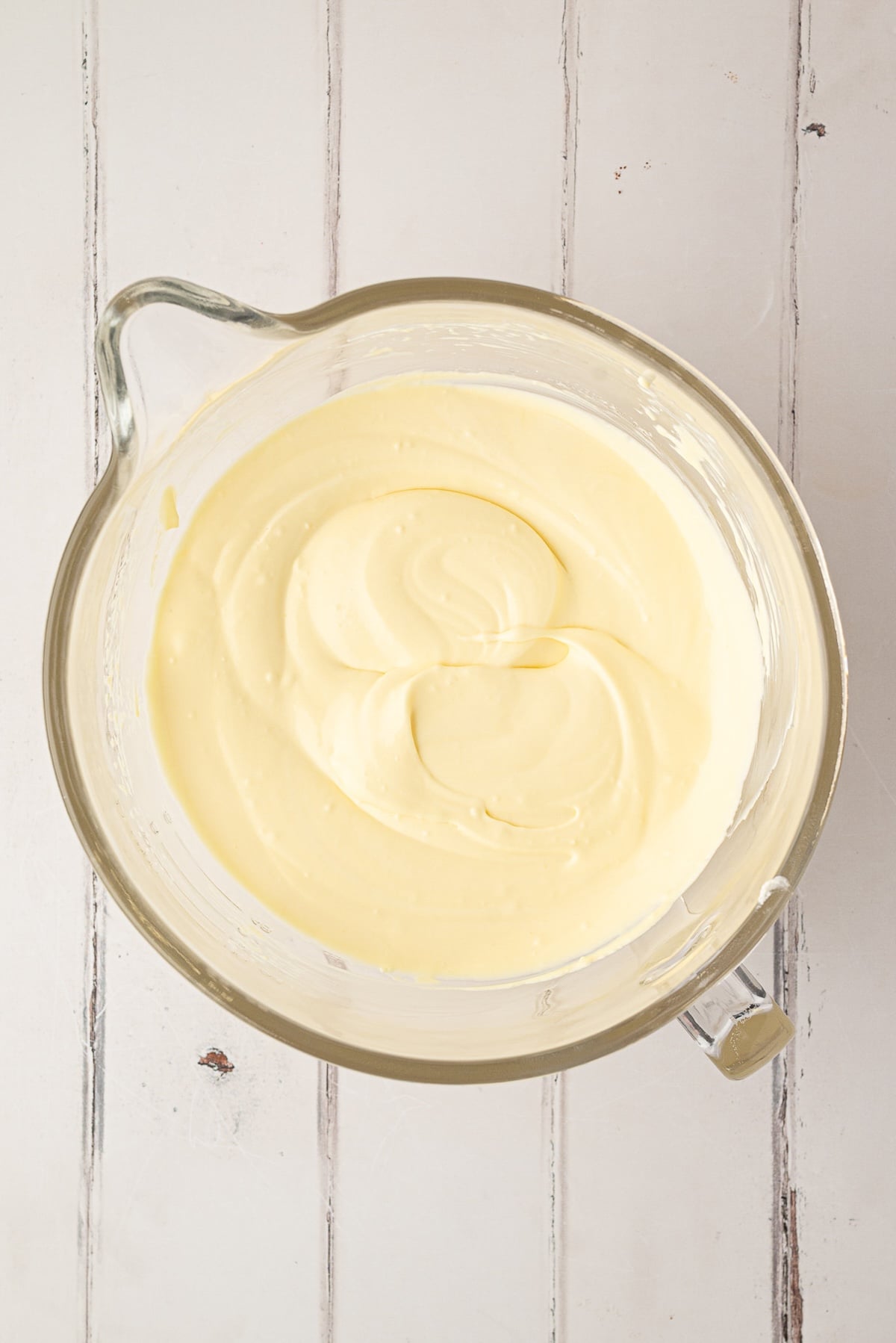 Gently folding whipped topping into the cream cheese and pudding mixture with a spatula to create a fluffy texture.