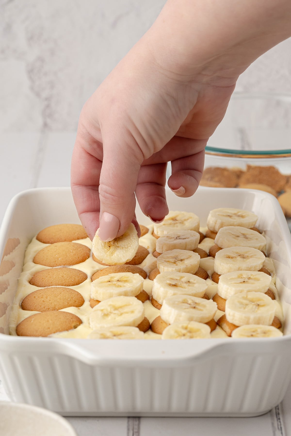 Adding the second layer of vanilla wafers and banana slices.