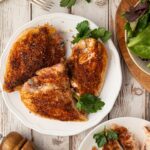 An overhead view of perfectly oven-roasted bone-in split chicken breasts featuring a savory Texas dry rub and golden crispy skin, served on a plate.