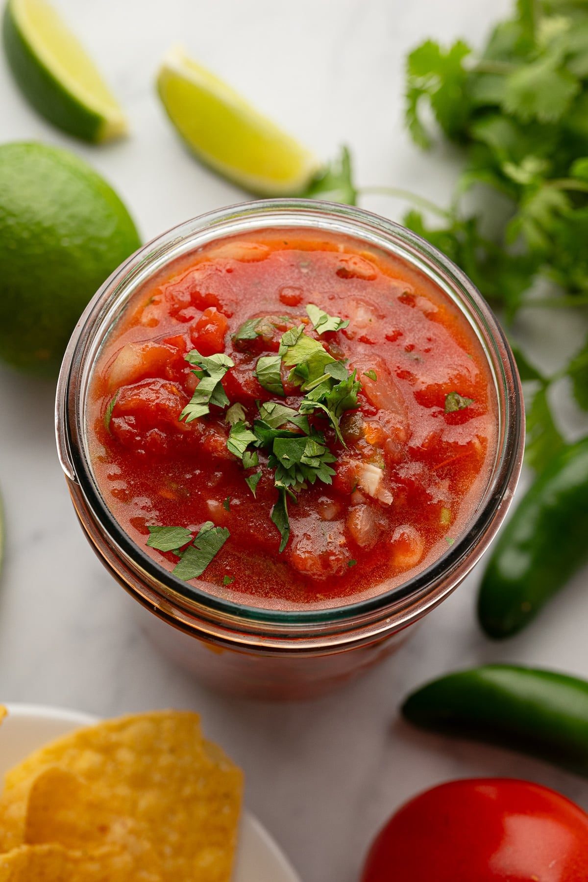 The best fresh homemade chunky salsa in a jar, showing chunks of white onion and pieces of cilantro.