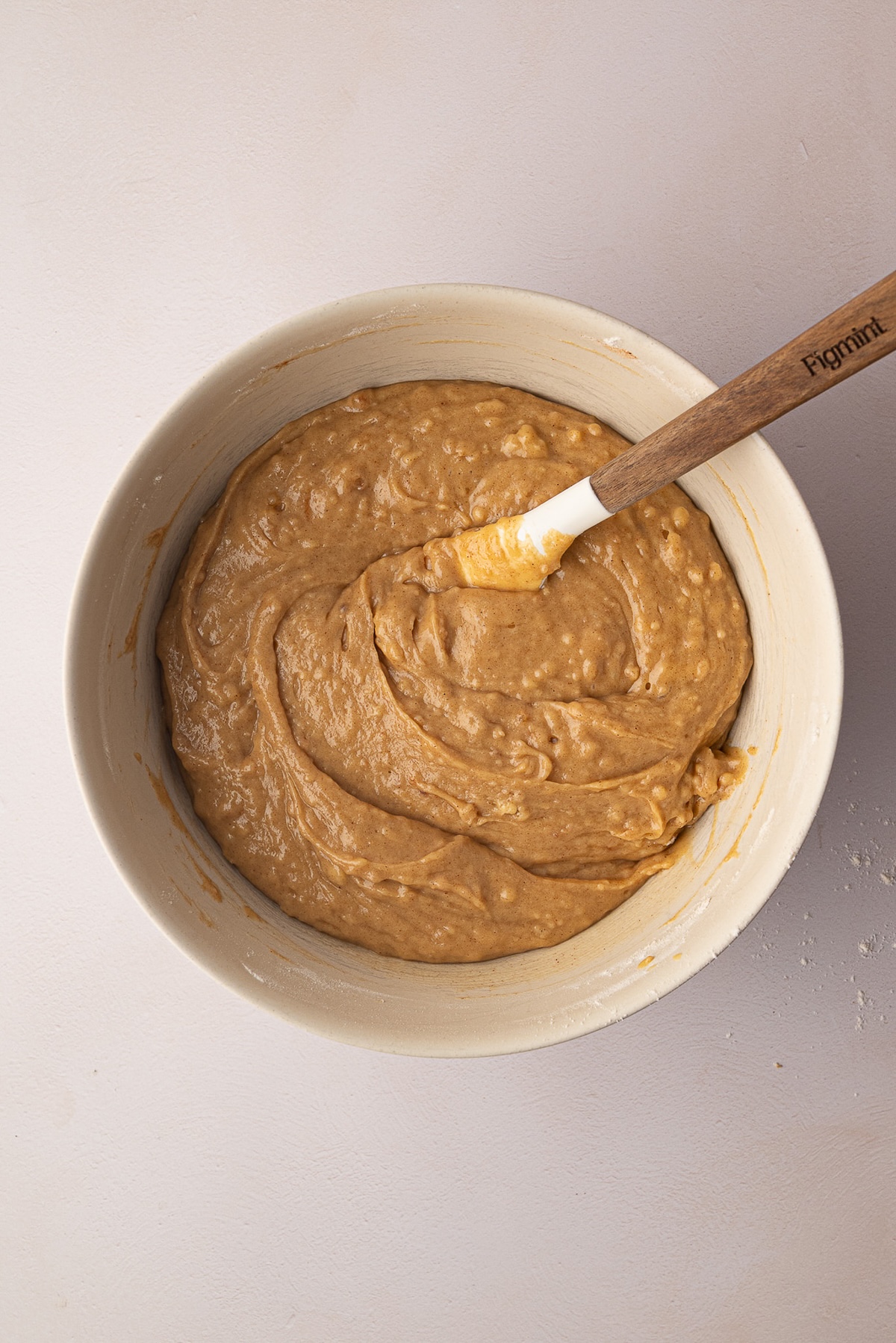 Stirring all-purpose flour, baking soda, and ground cinnamon into the wet ingredients for a zucchini cake batter.