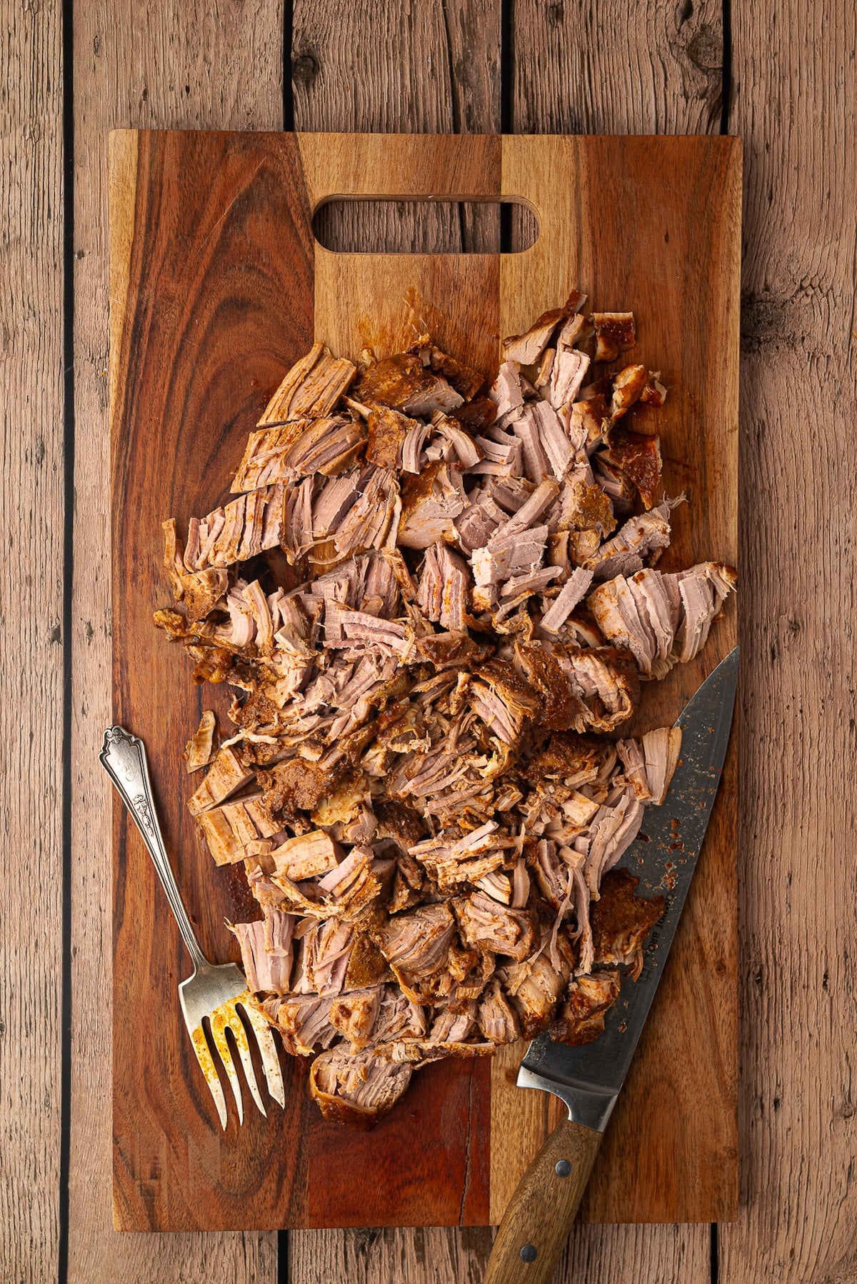 Pork tenderloin on a cutting board, shredded.