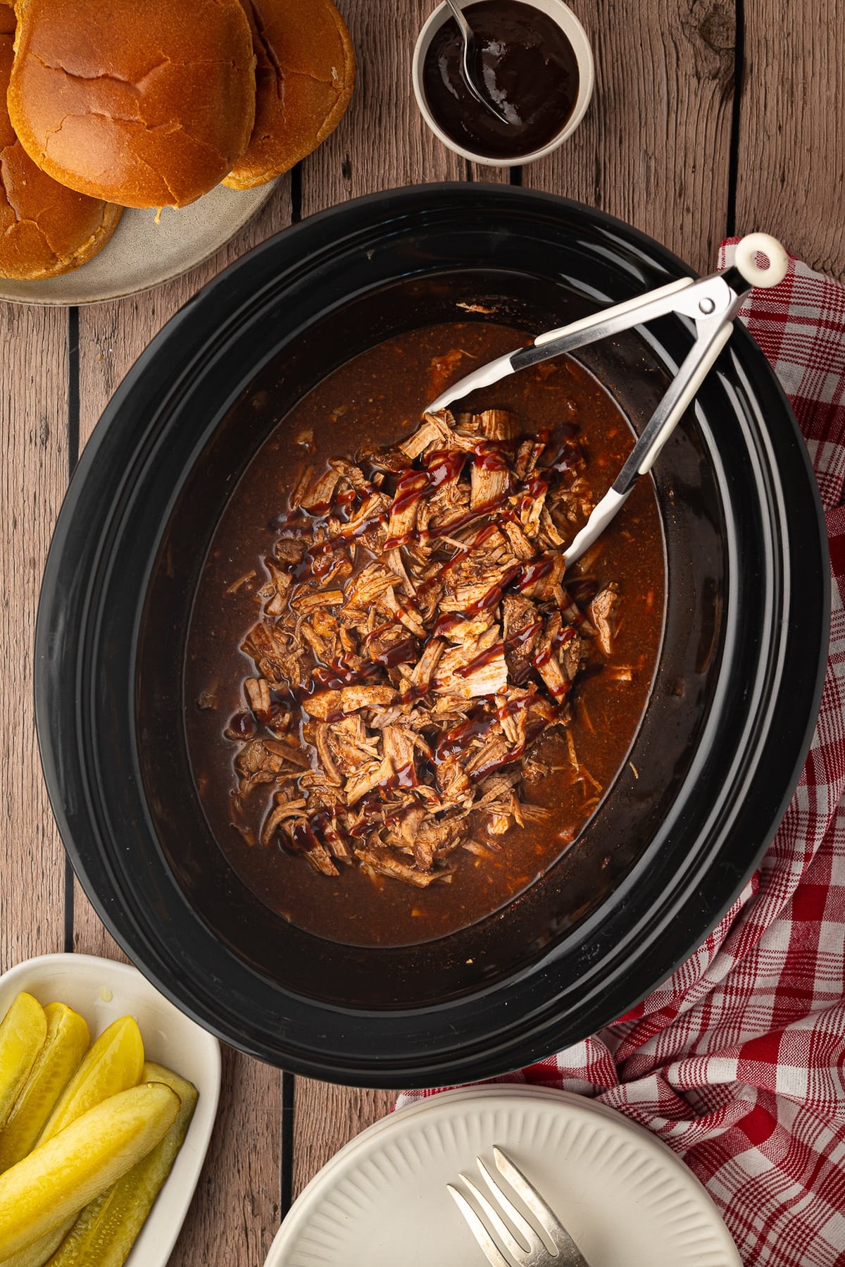 Tender shredded pork tenderloin glistening in a sweet and savory pineapple barbecue sauce inside a slow cooker pot.