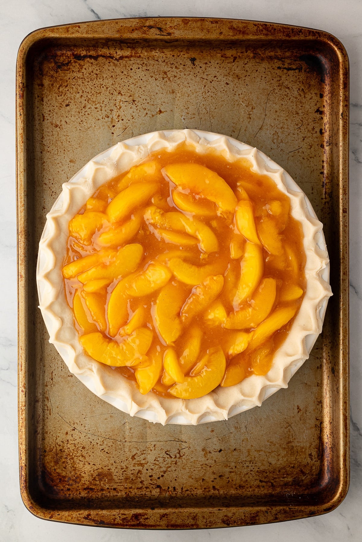 Thick peach pie filling piled high inside an unbaked deep-dish pie crust, leaving a one-third inch space at the top.