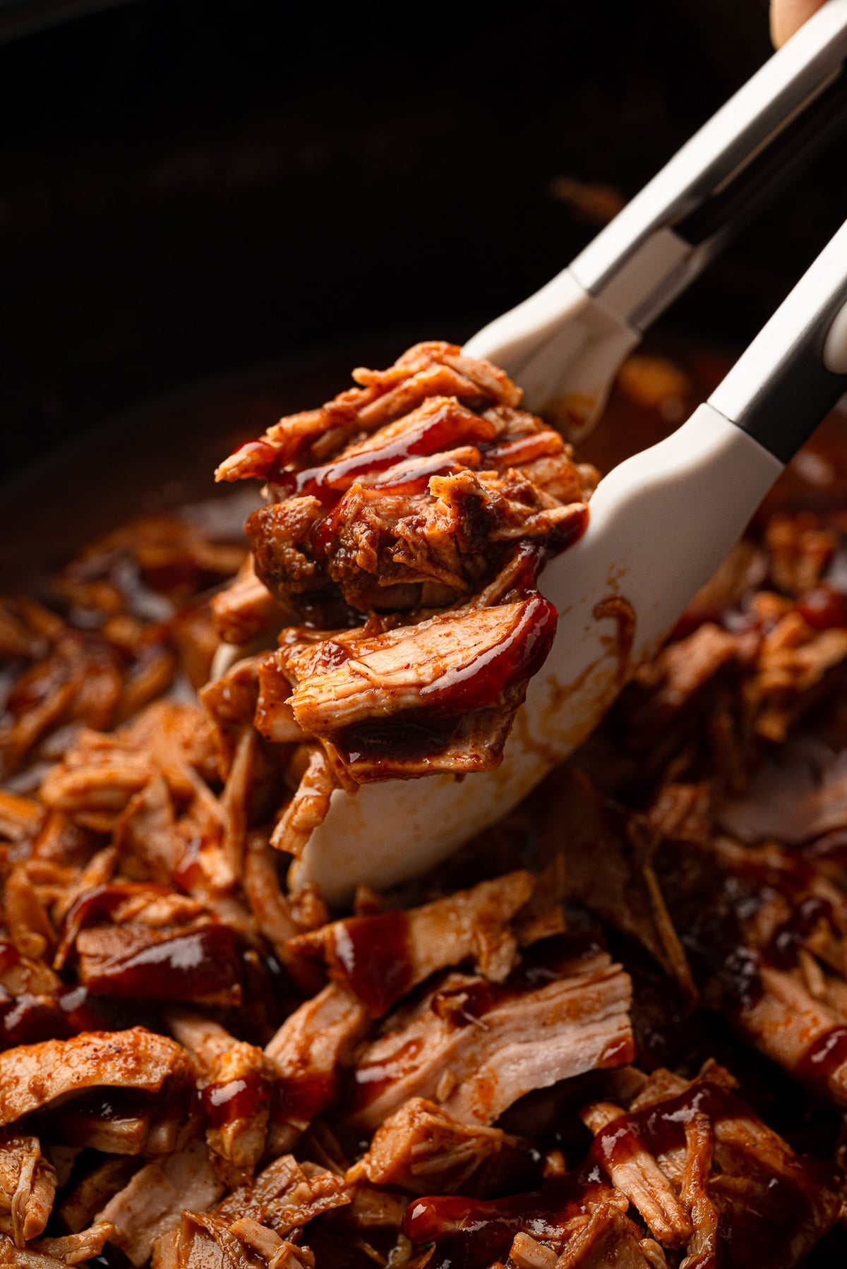 A closeup of shredded pork tenderloin in a pineapple barbecue sauce inside a crockpot.