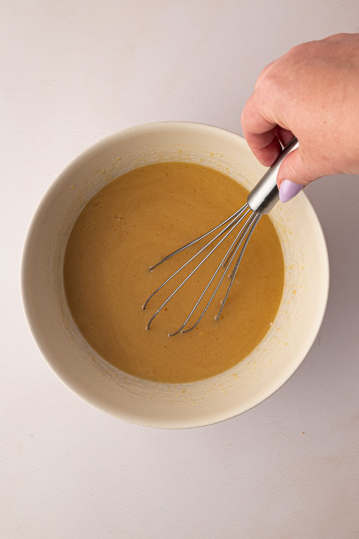 Whicking together brown sugar, melted butter, oil, eggs, buttermilk, and vanilla extract in a large ceramic mixing bowl.