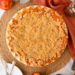 A whole homemade peach crumble pie fresh from the oven, featuring a golden-brown streusel topping and bubbling juices.