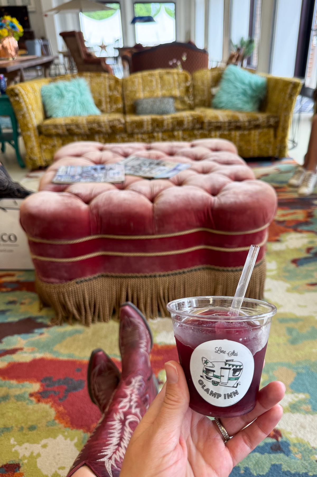 A cup of frozen sangria from the Lone Star Glamp Inn during Antiques Week with vintage plush seating in the back.