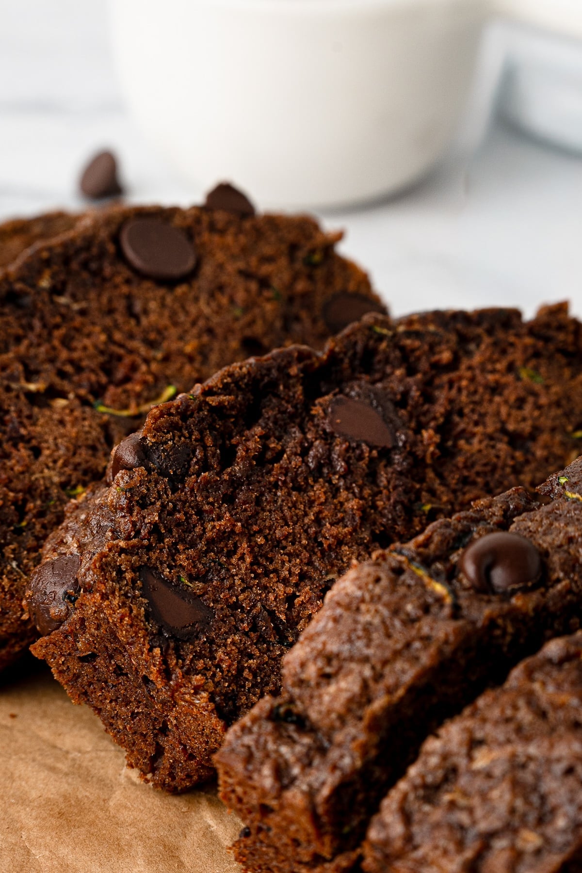 Close-up of a slice of chocolate zucchini bread showing the moist, chocolatey crumb and melted chocolate chips.