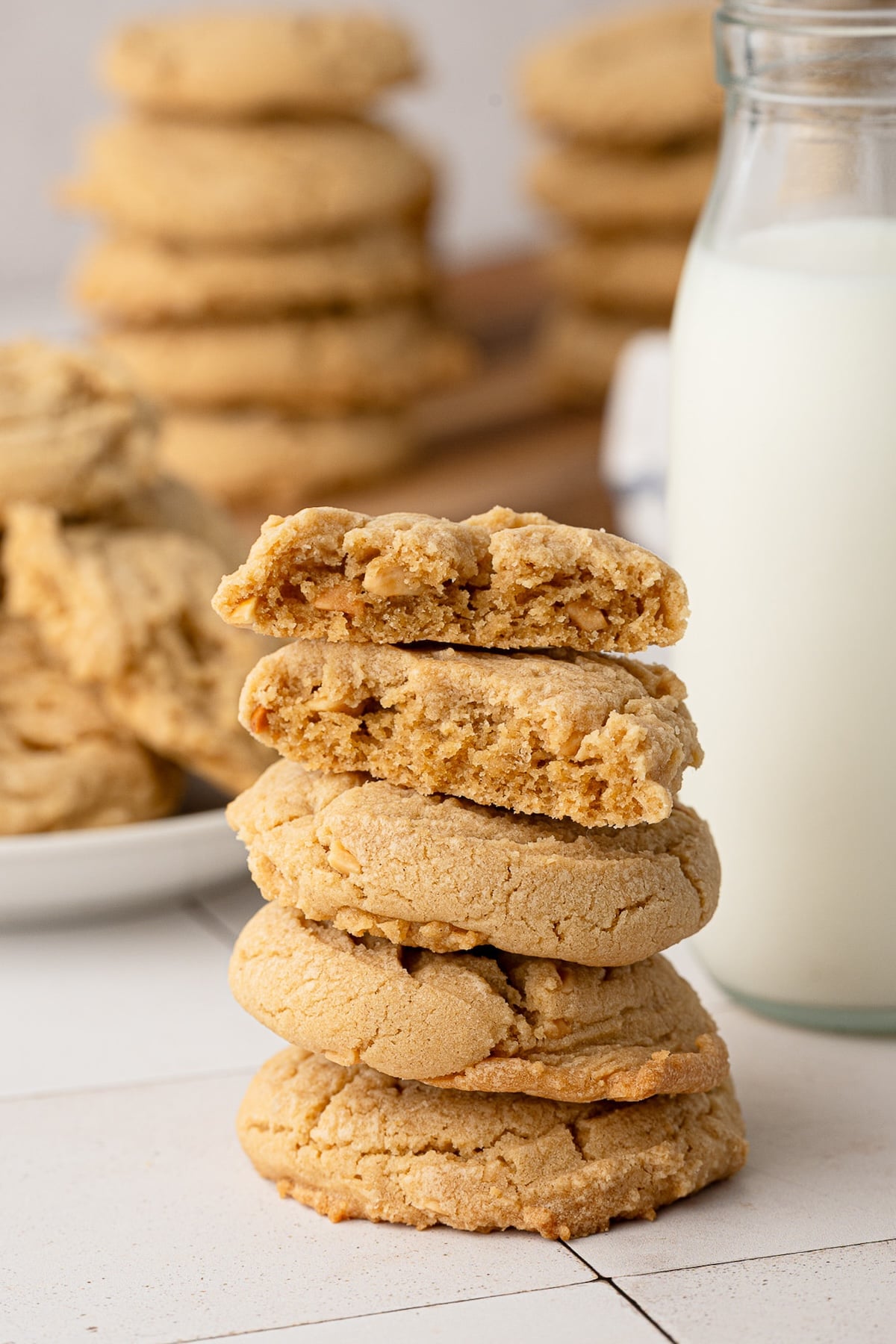 A stack of the best peanut butter cookies on the counter with a glass of milk.