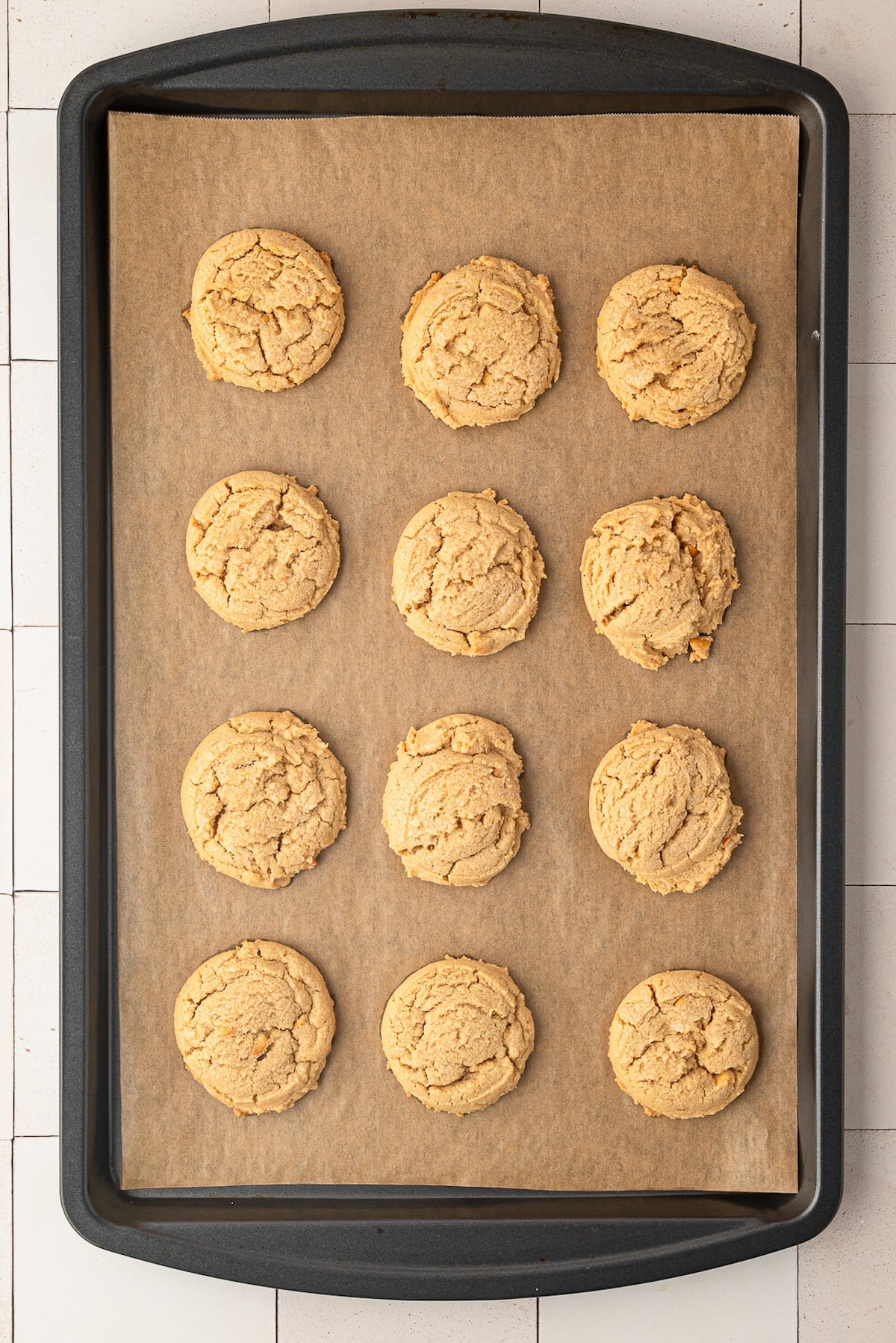 A baking sheet with a dozen peanut butter cookies fresh out of the oven.
