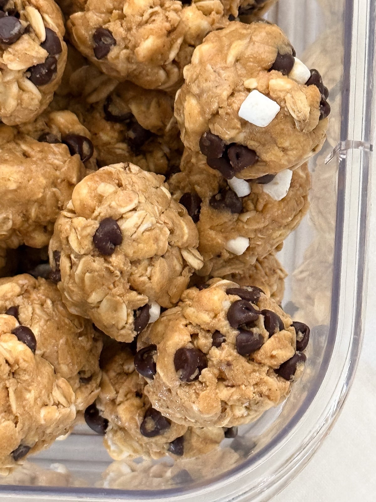 Closeup of s'mores protein bites showing oats, miniature chocolate chips, and marshmallow bits.