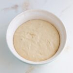 Texas kolache dough after the first rise in a ceramic mixing bowl.