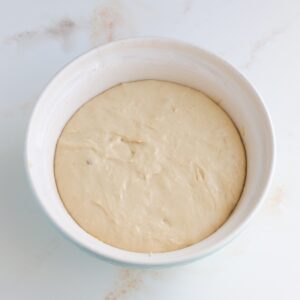 Texas kolache dough after the first rise in a ceramic mixing bowl.