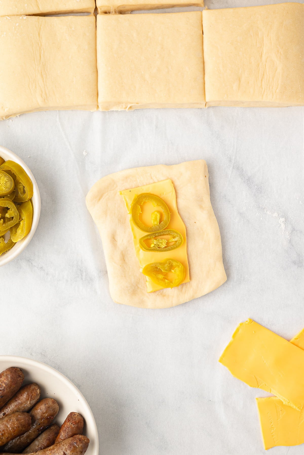 Placing jalapeno slices on the cheese for the kolache assembly.