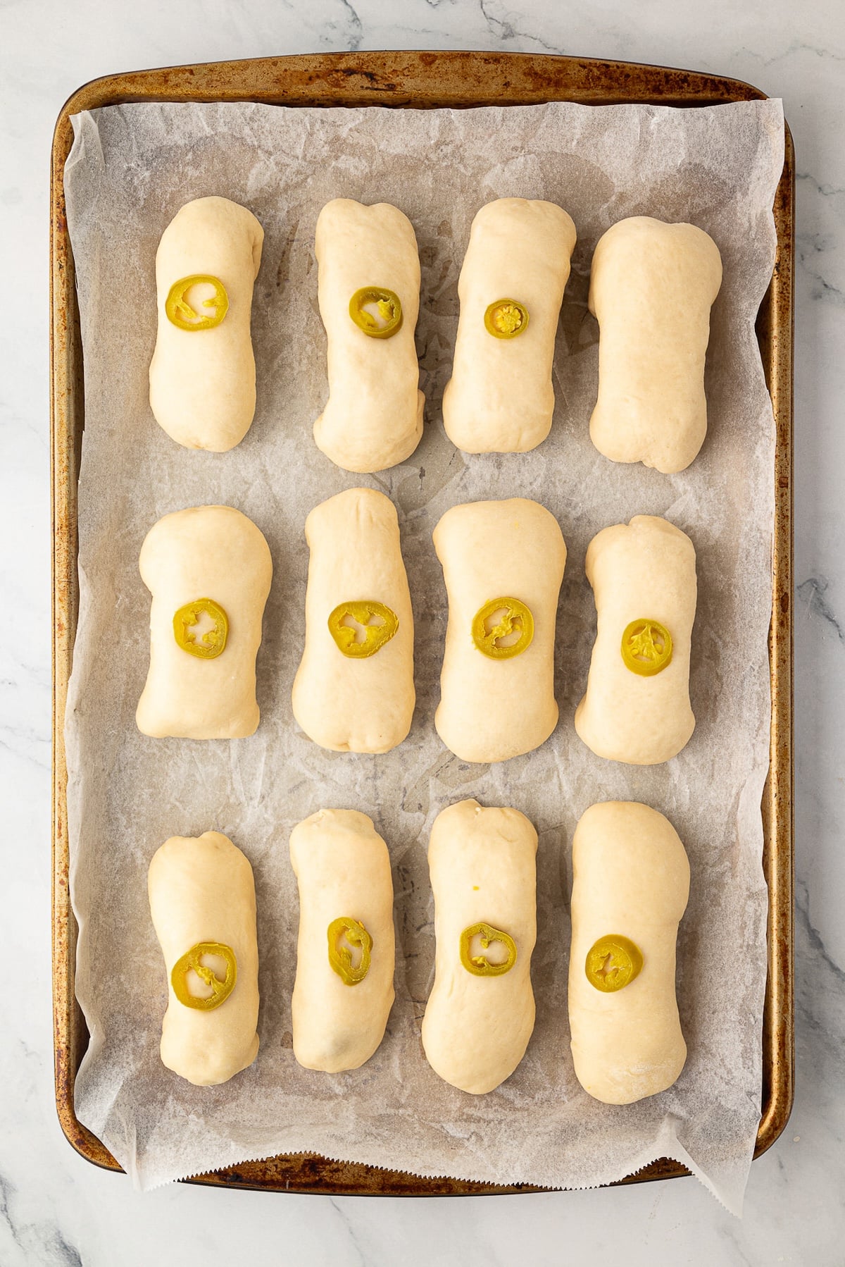 A baking sheet of a dozen breakfast pastries after shaping, before their first rise.