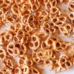 A closeup of pretzels heavily coated in melted butterscotch chips and garnished with flaky sea salt.