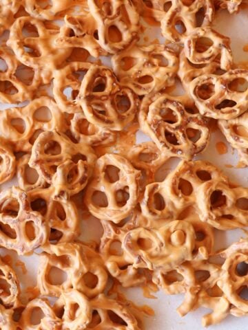 A closeup of pretzels heavily coated in melted butterscotch chips and garnished with flaky sea salt.
