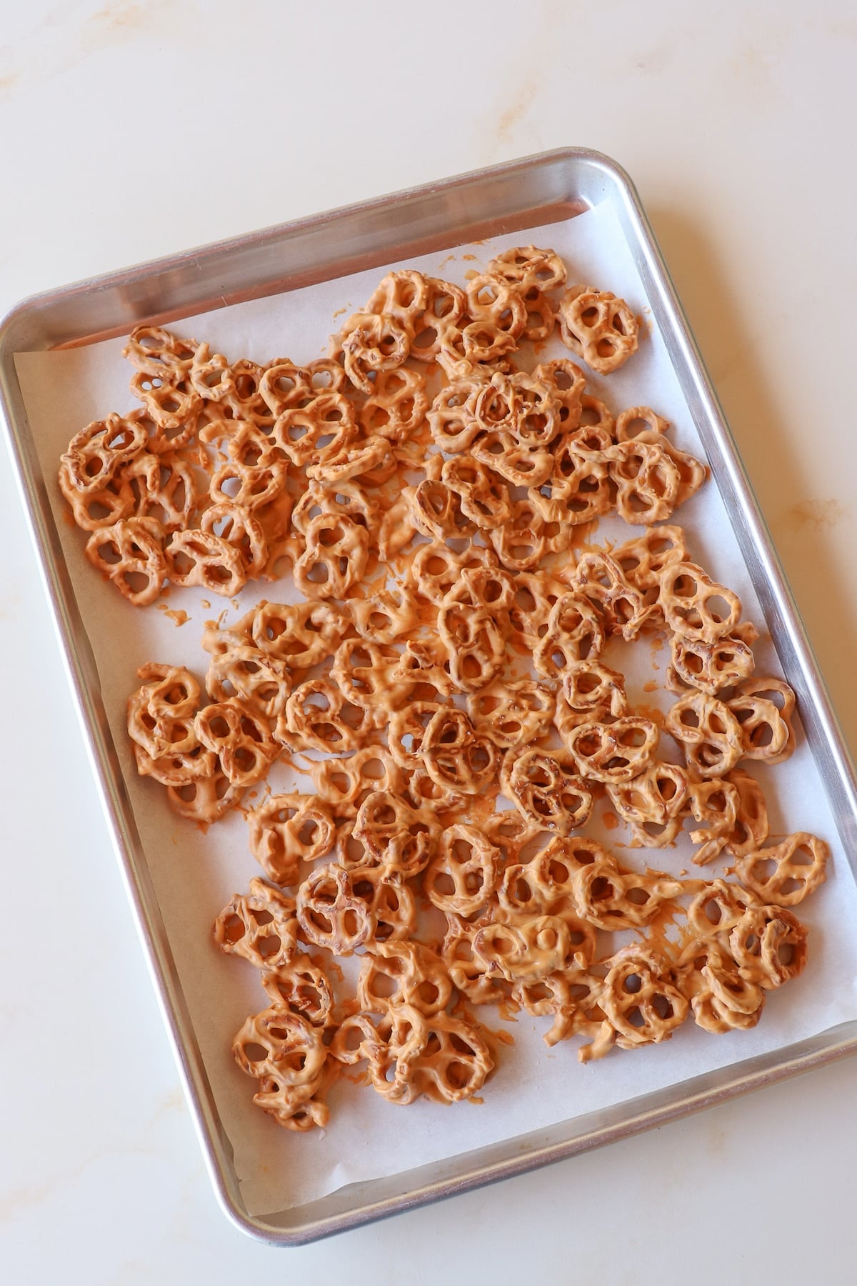 Butterscotch pretzels cooling on a parchment lined baking sheet.