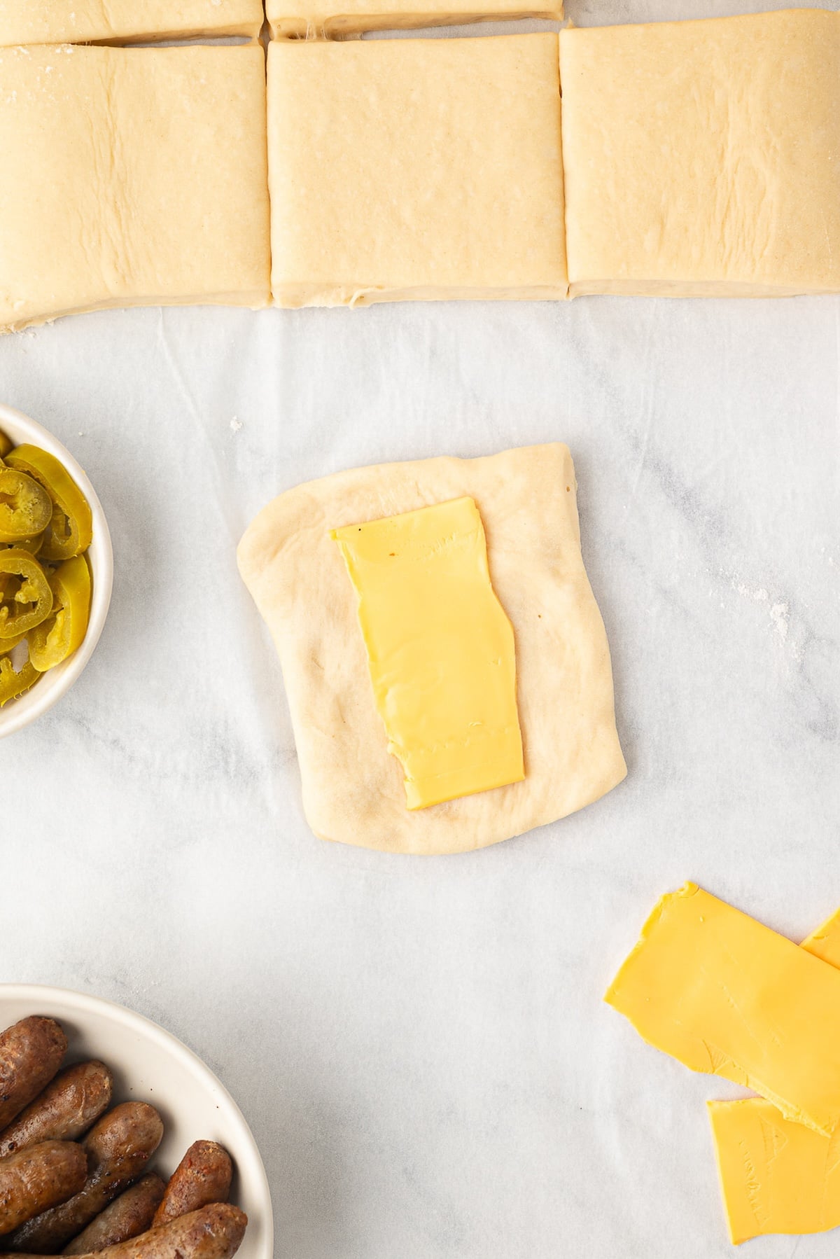 Layering ½ slice of cheese on a dough square.