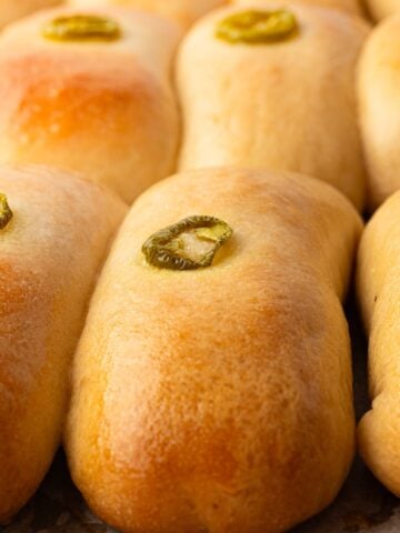 Golden brown, freshly baked jalapeno sausage cheese kolaches with jalapeno ring on top.
