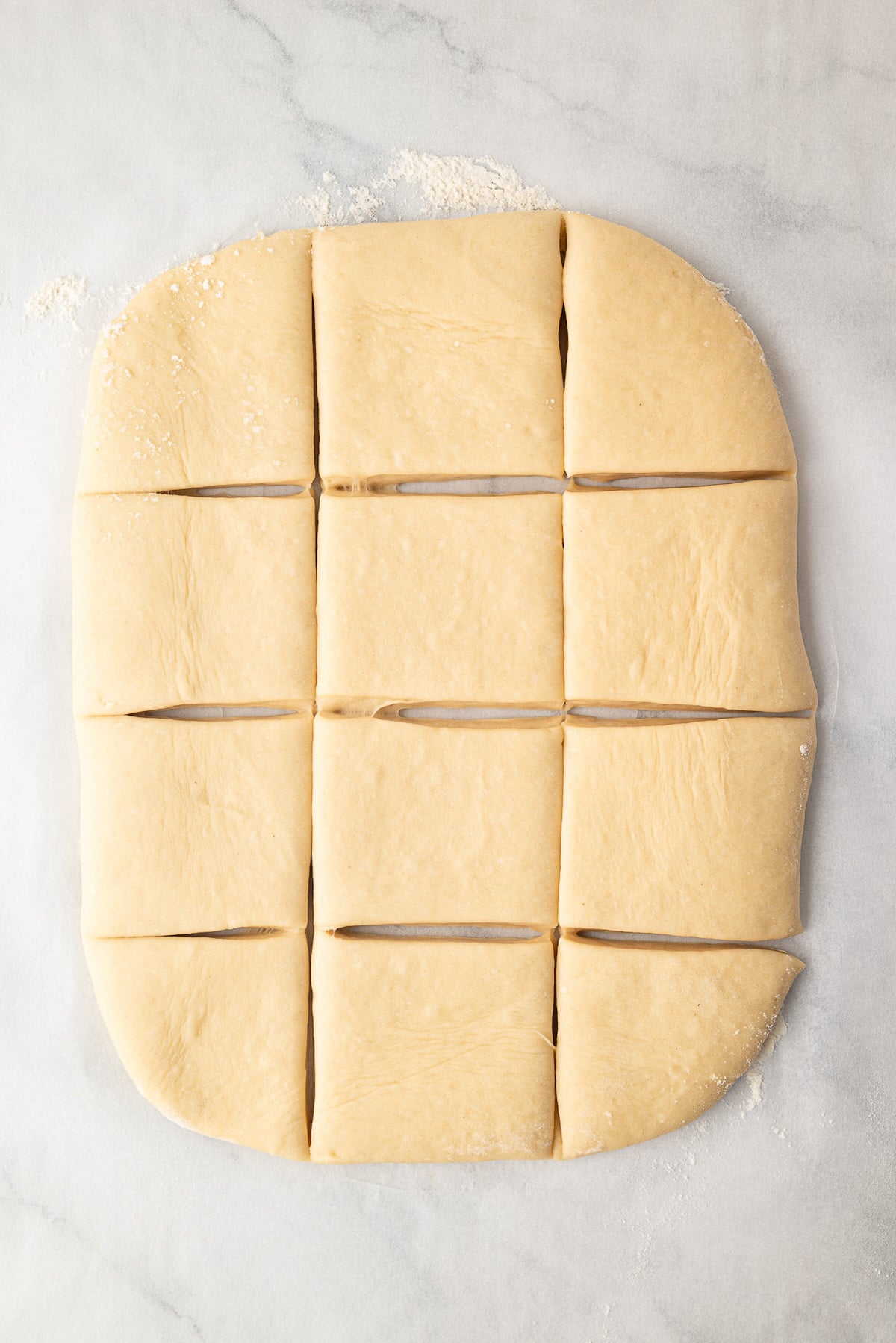 Kolache dough cut into 12 squares to make sausage kolaches.
